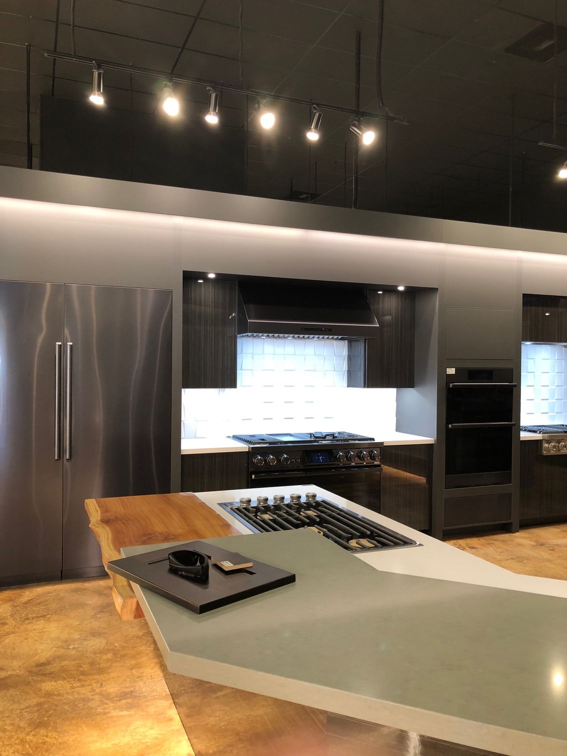 Modern kitchen with stainless steel appliances, dark cabinets, and a gray island.