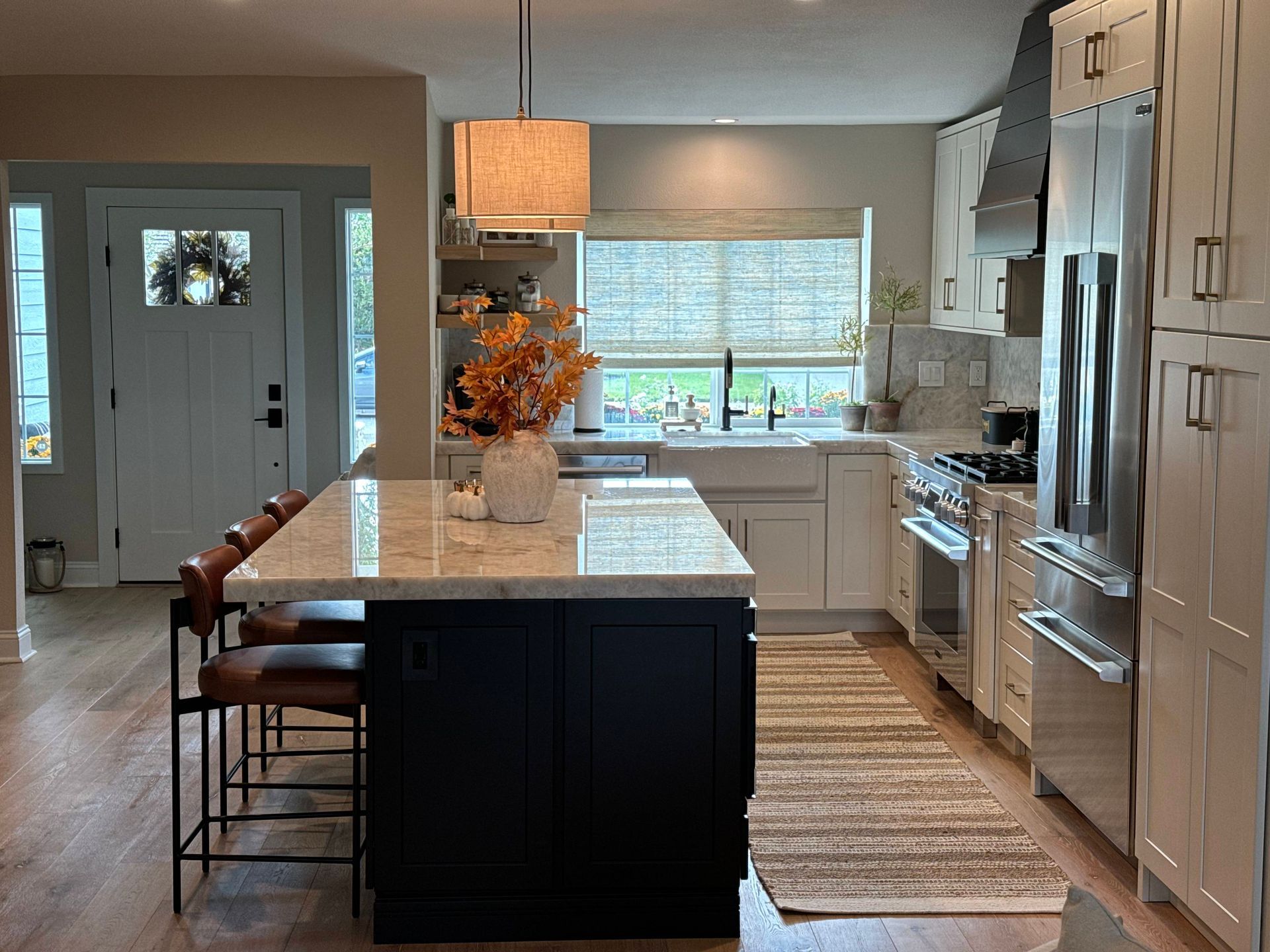 Kitchen with navy island, light countertops, white cabinets, stainless steel appliances, and wood flooring.