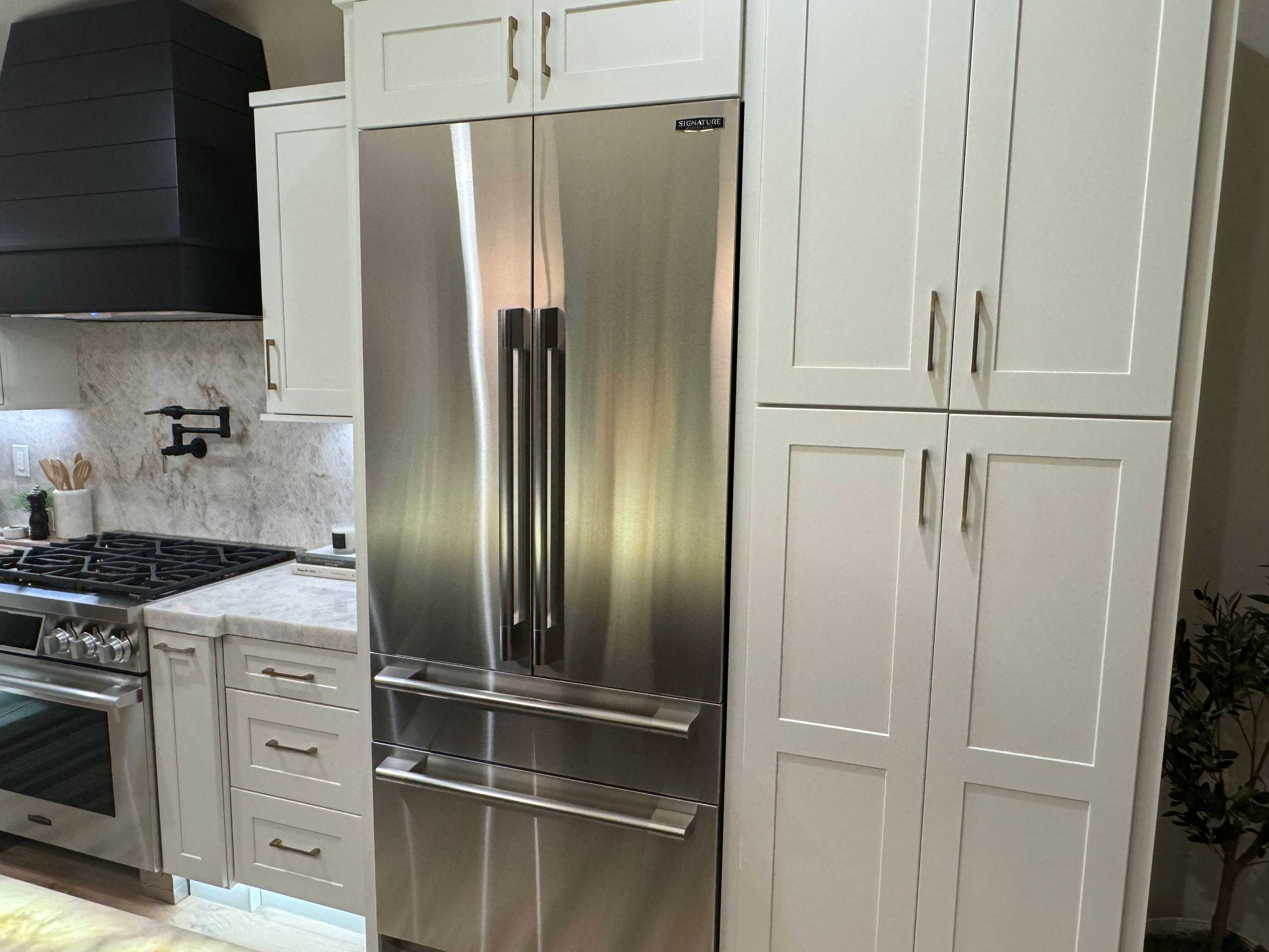 A kitchen with white cabinets , stainless steel appliances , and a stove top oven.