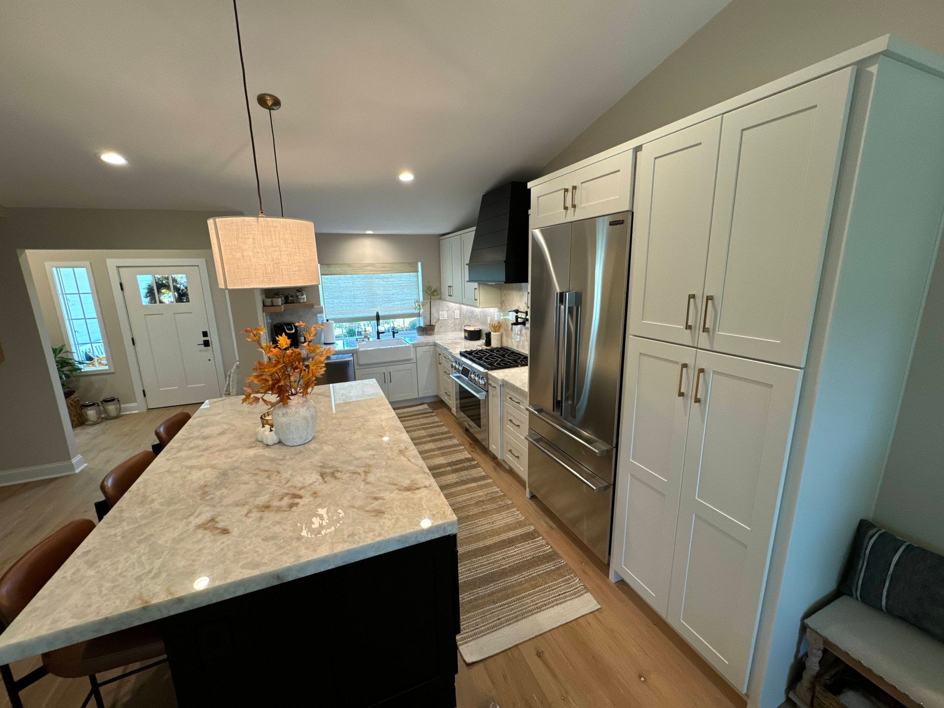 Modern kitchen with white cabinets, stainless steel appliances, black island, and light wood floors.