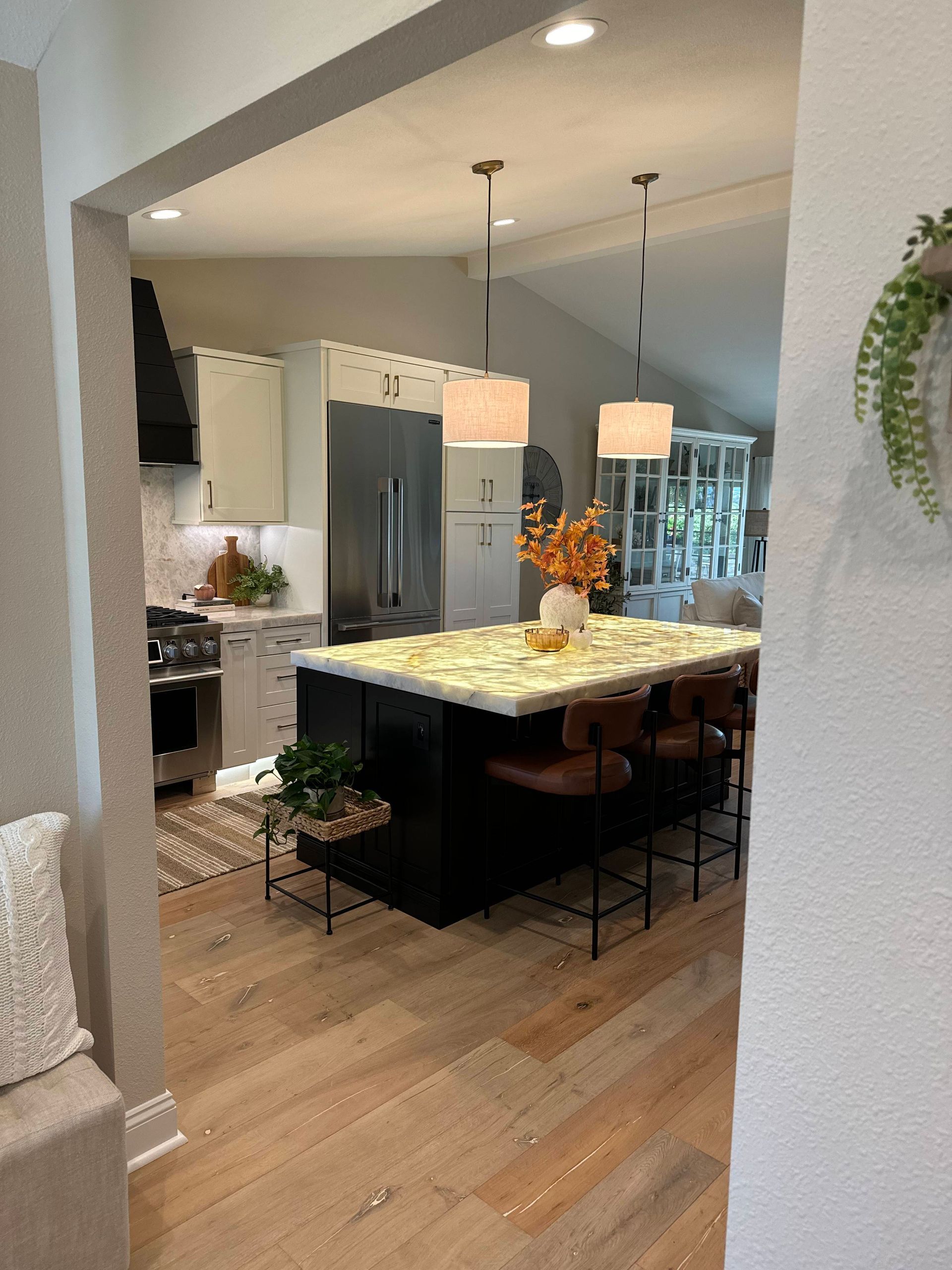 Kitchen with a black island, light wood floor, and stainless steel appliances.