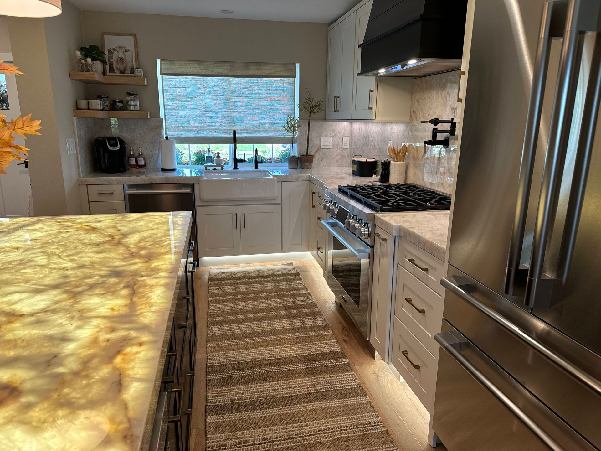 A kitchen with white cabinets, stainless steel appliances, marble countertops, and a rug.