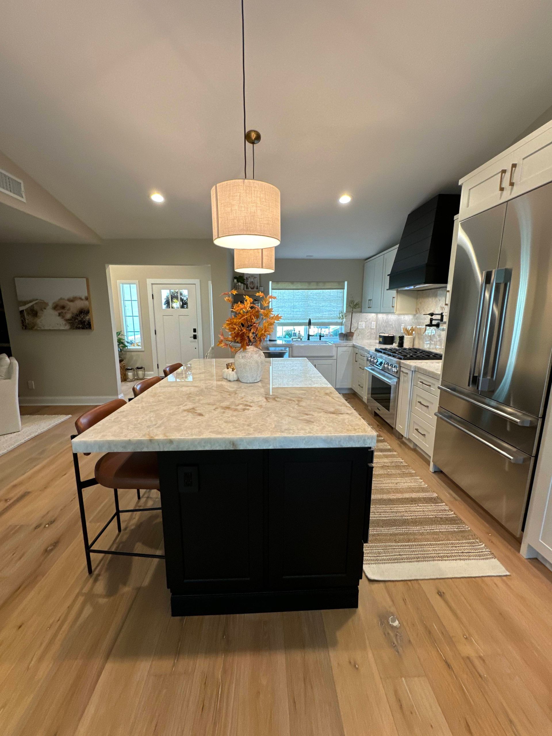Kitchen with a black island, white countertops, and wooden floors.