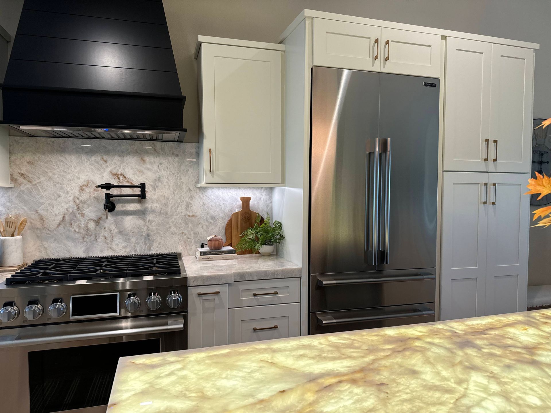 Kitchen with stainless steel appliances, white cabinets, and a black range hood.