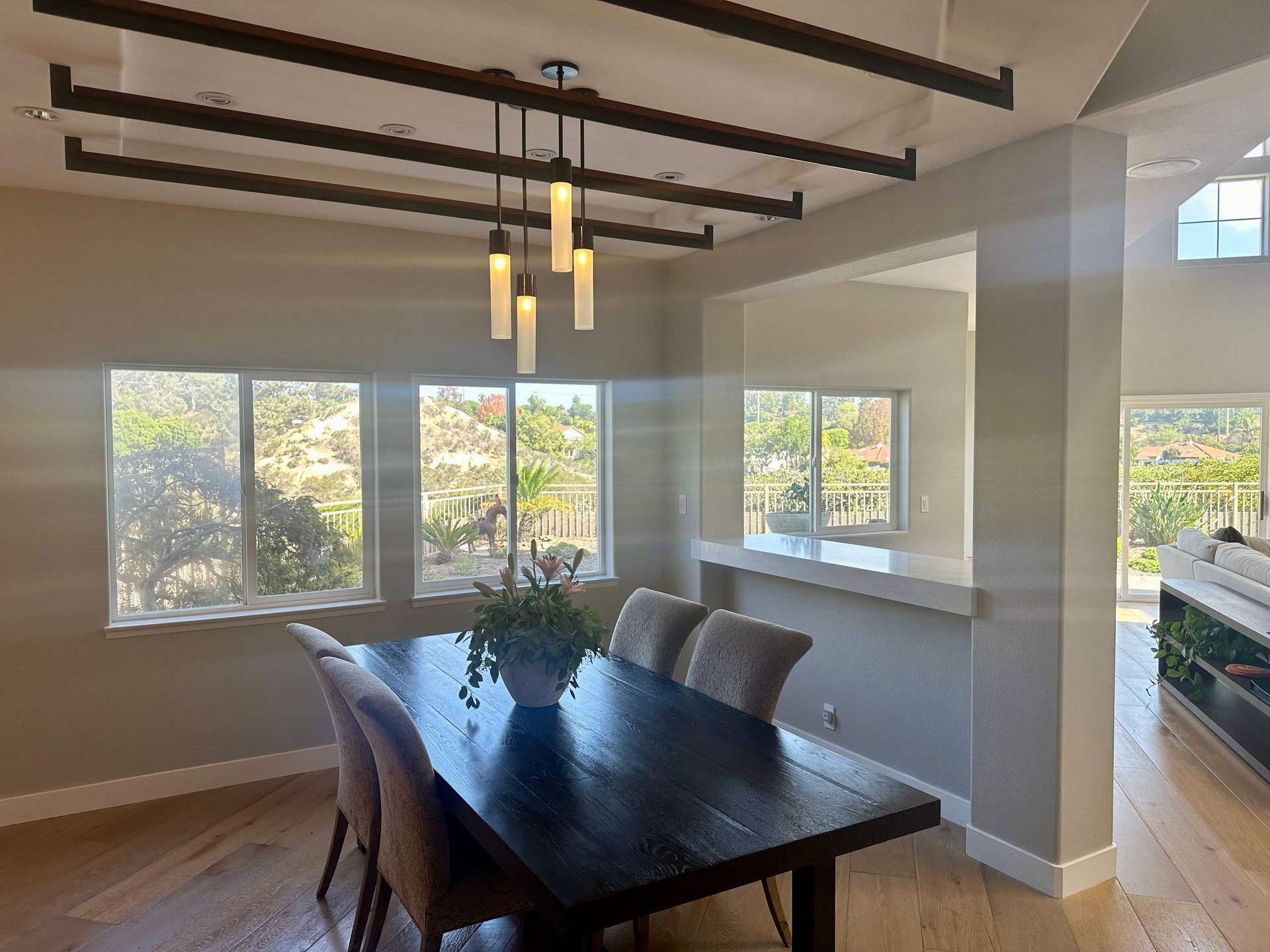 Dining room with dark wood table, chairs, windows, and decorative ceiling beams.