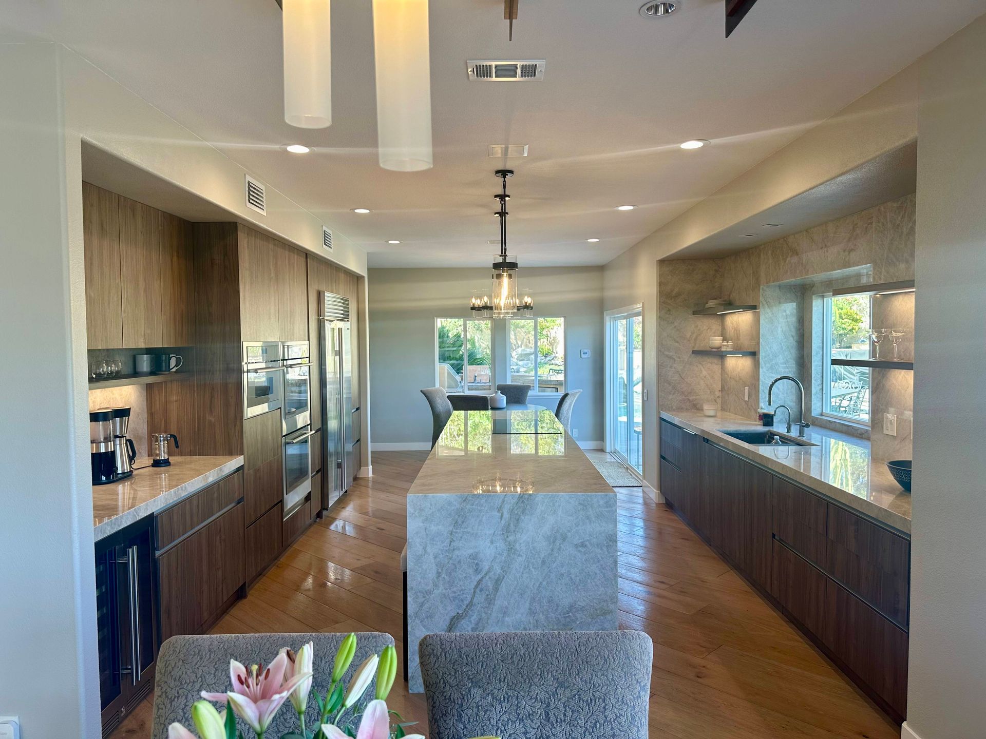 Modern kitchen with long island and dark wood cabinets; neutral color scheme, well lit.