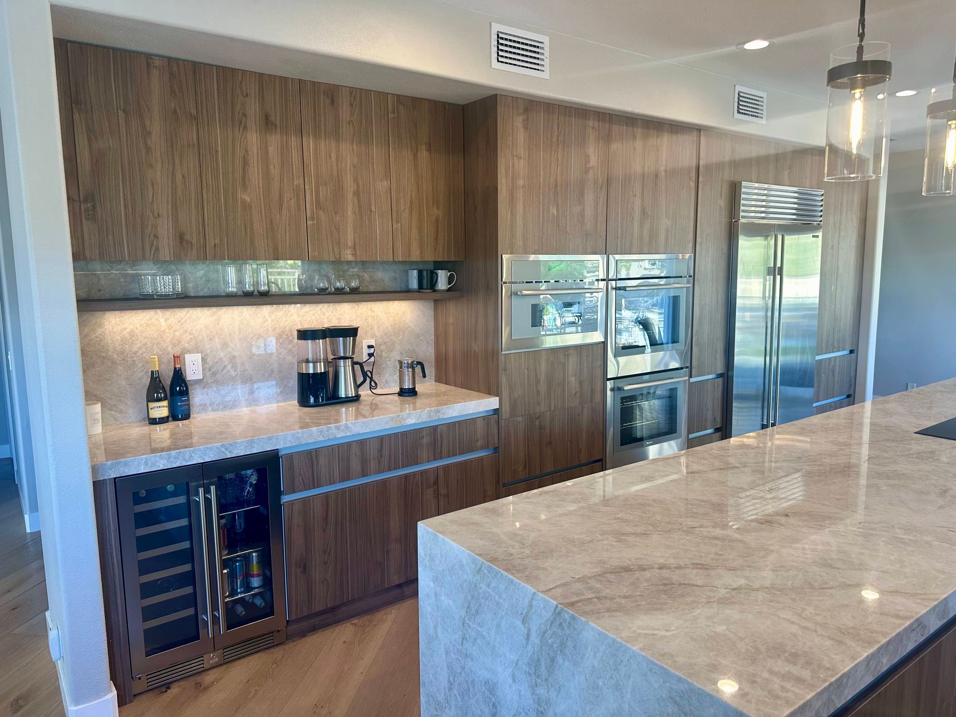 Modern kitchen with wood cabinets, stainless steel appliances, and marble countertops.