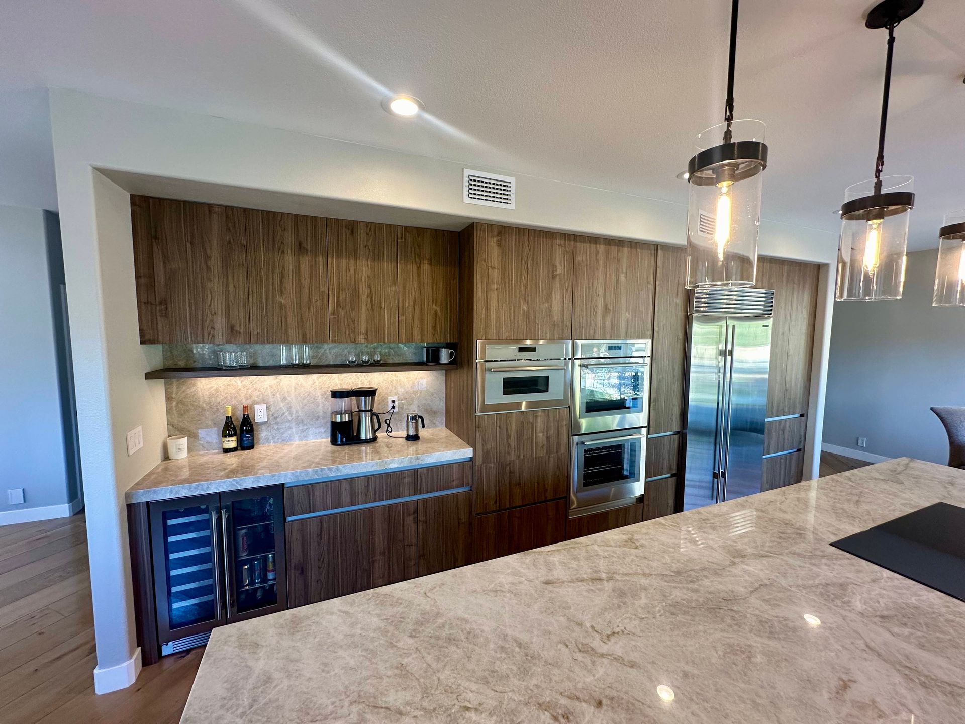 Modern kitchen with wood cabinets, stainless steel appliances, and a marble countertop.