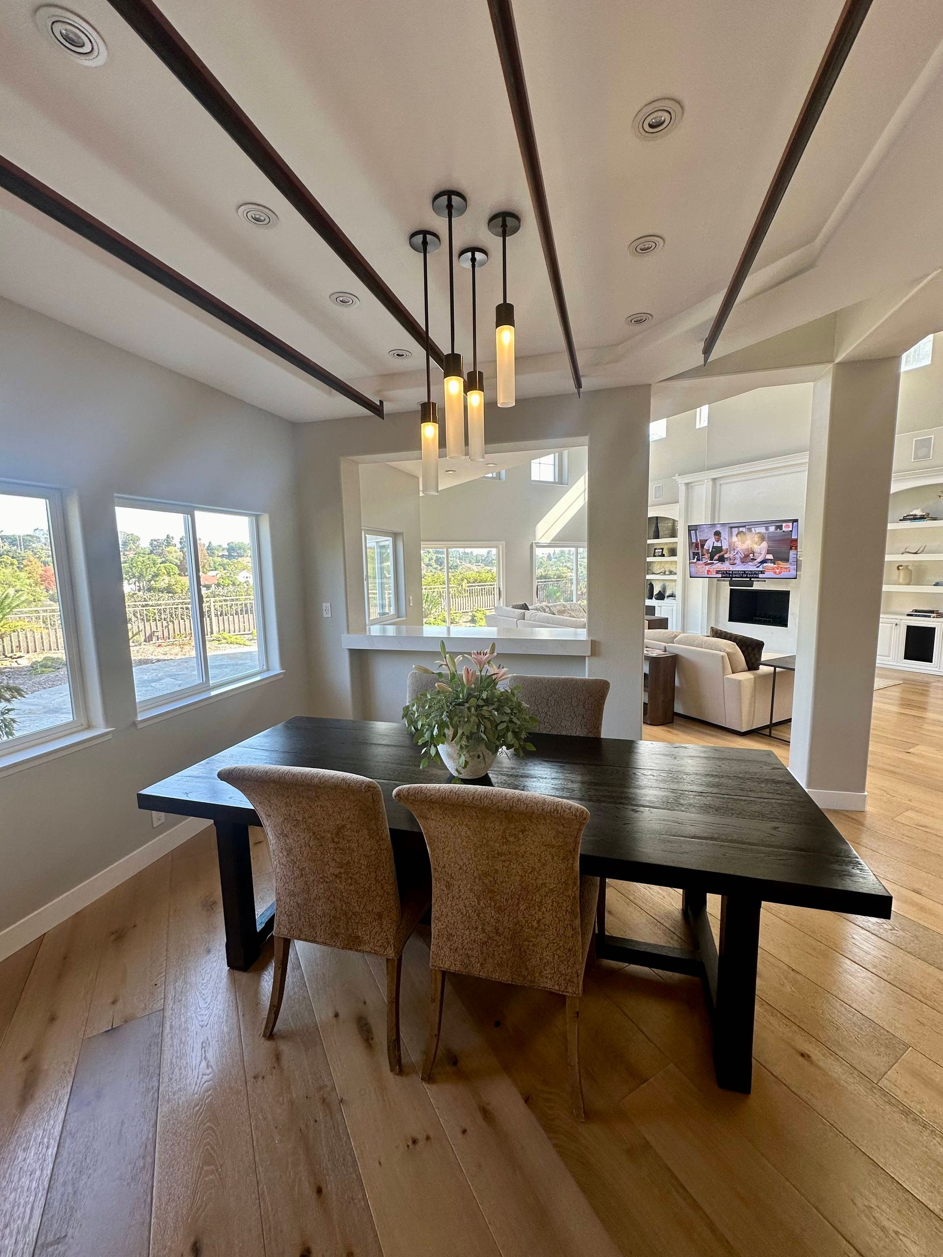 Dining room with a dark wooden table, wicker chairs, and pendant lighting.