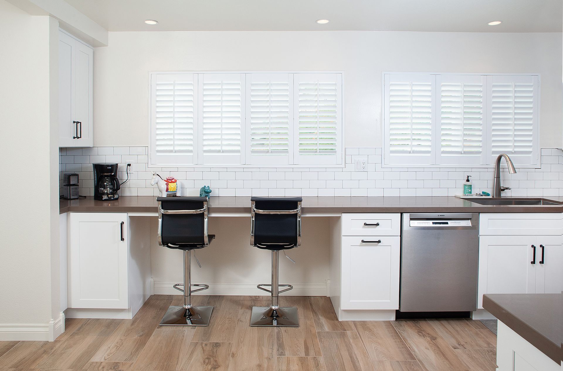 Accessible kitchen with white cabinets, stainless steel appliances, and bar seating.