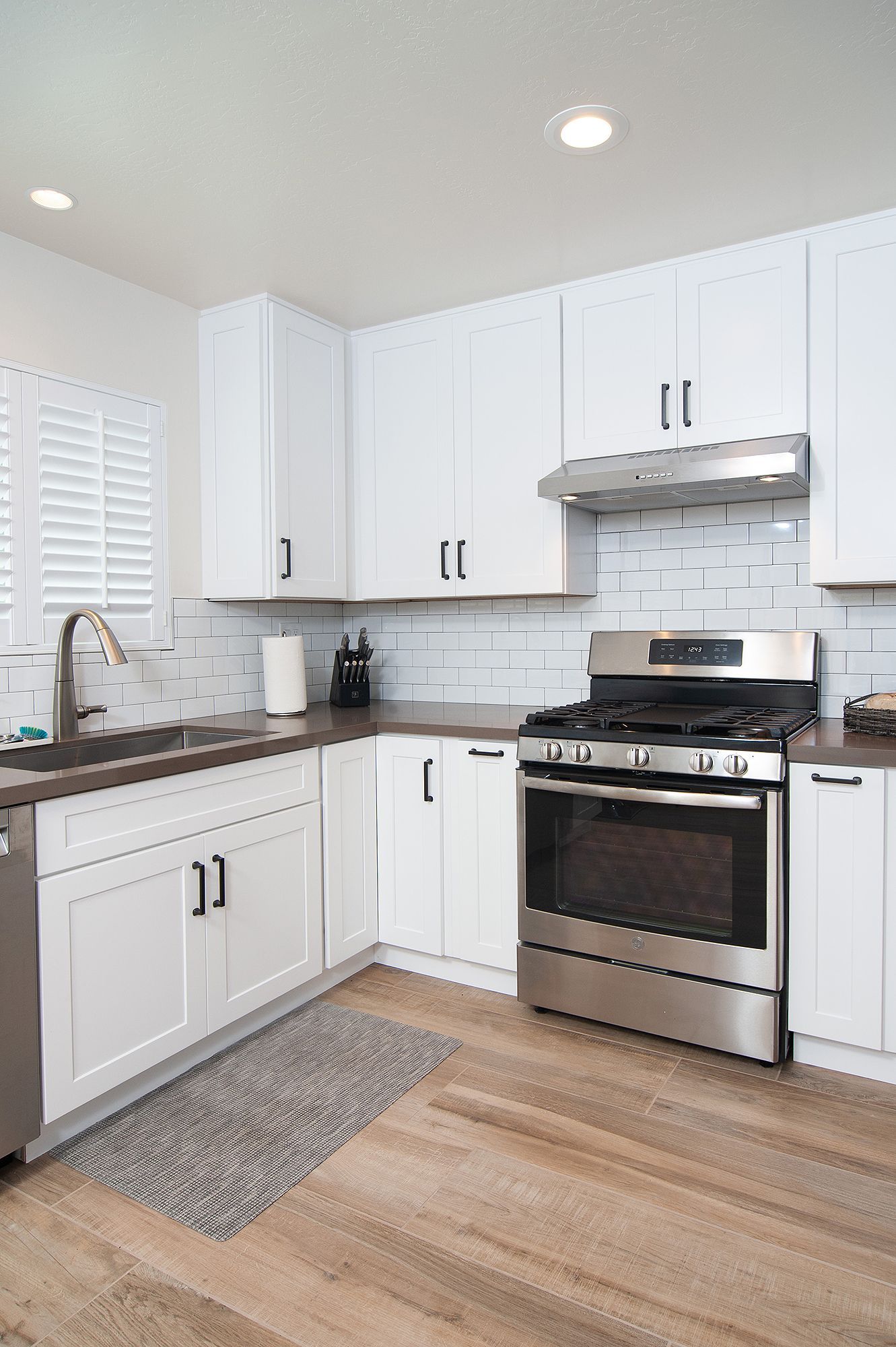 White kitchen with stainless steel appliances and wood-look floors.