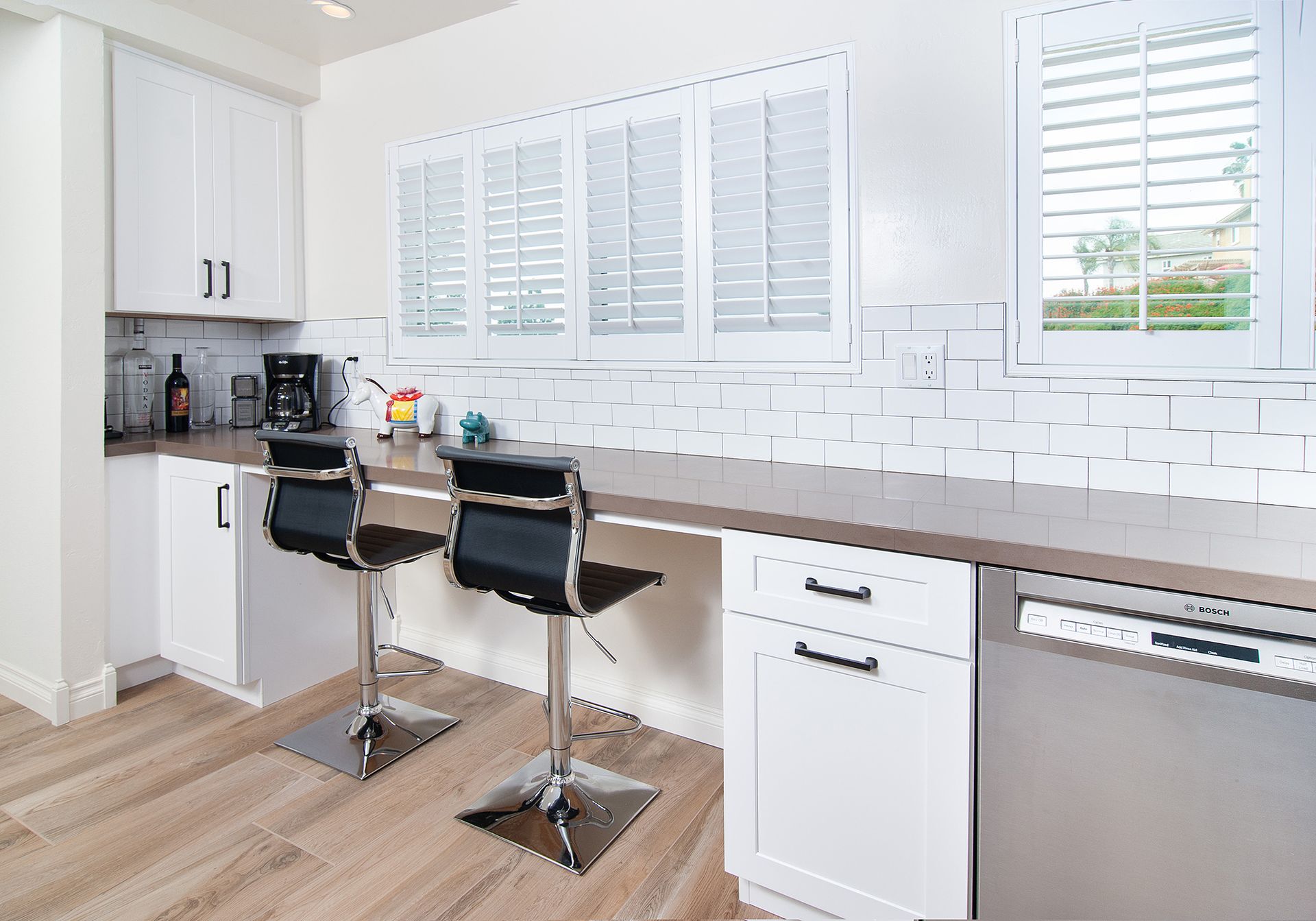 Kitchen with white cabinets, bar seating, and a dishwasher.