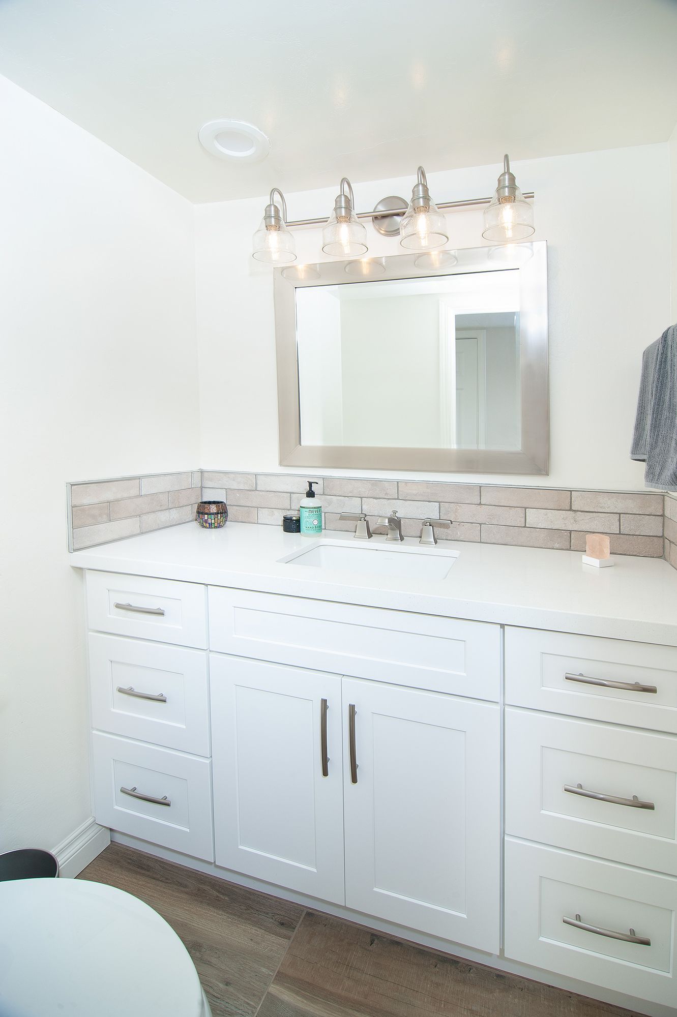 White bathroom with vanity, mirror, and bright lighting.
