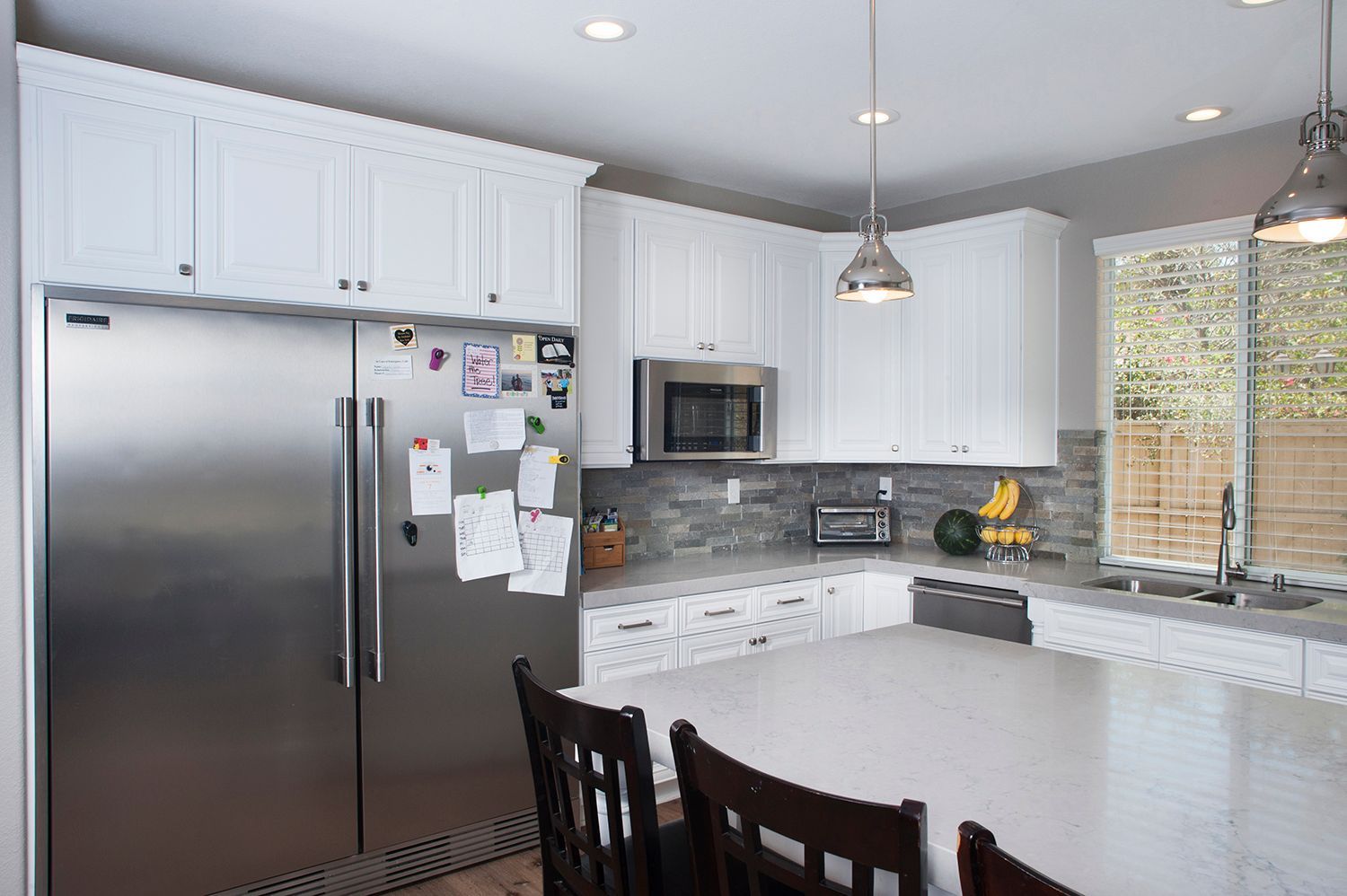 White kitchen with stainless steel appliances, white cabinets, and a large island.