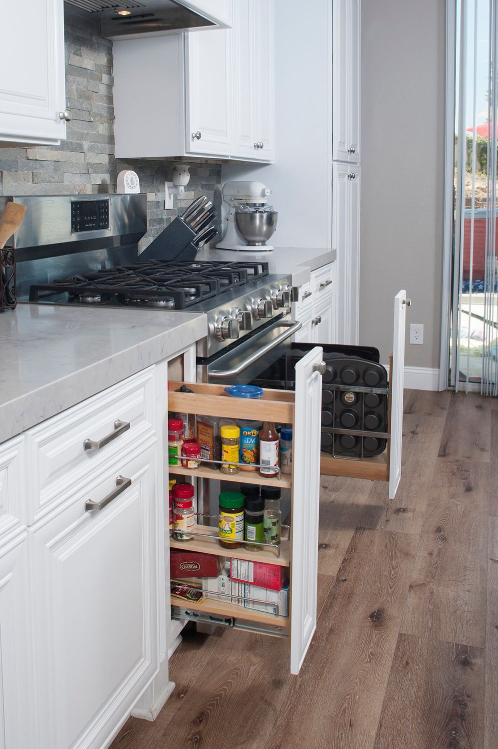 White kitchen with pull-out spice rack and wine rack next to stove.