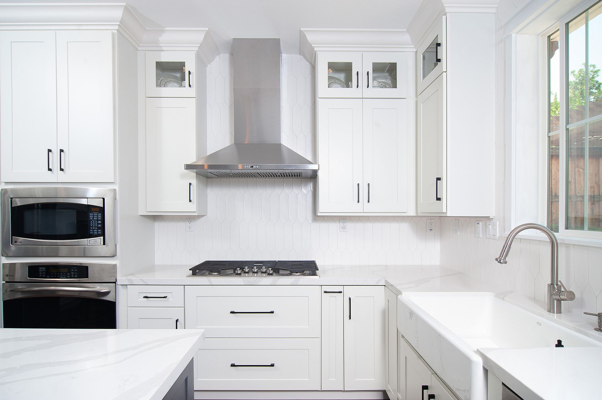 White kitchen with stainless steel appliances and farm sink.