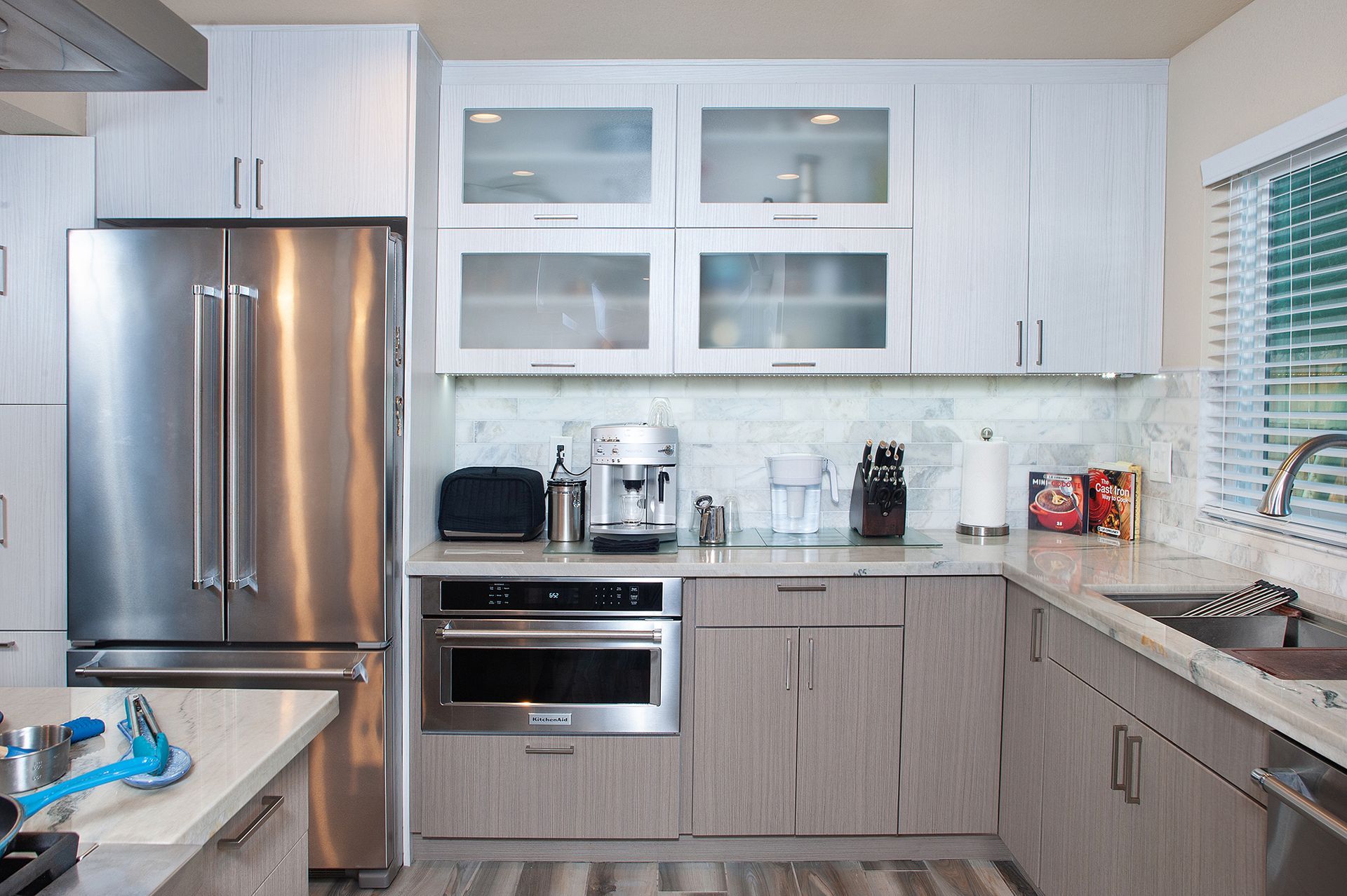 Modern kitchen with stainless steel appliances, light wood cabinets, and a window.