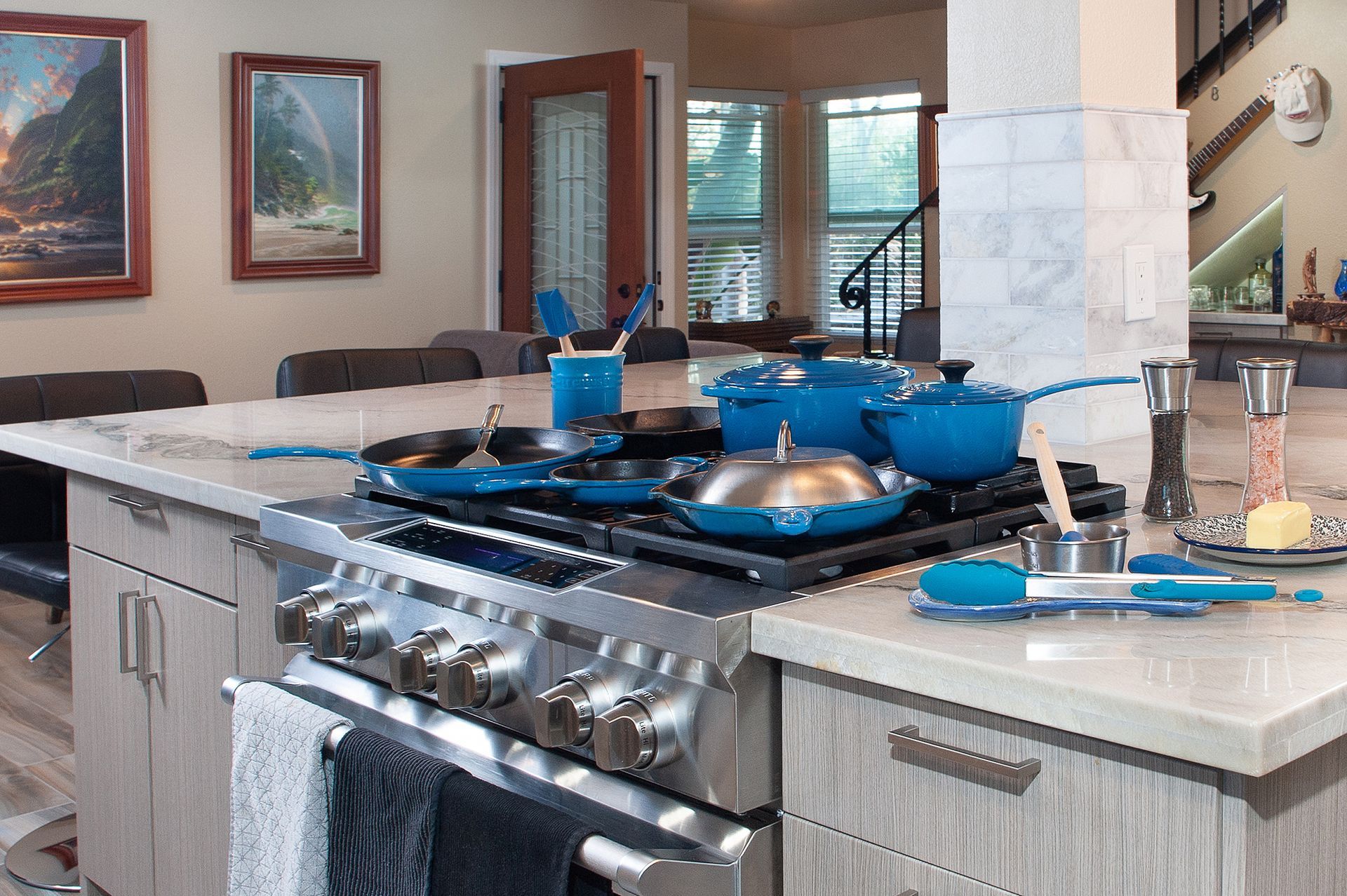 A kitchen with a stainless steel stove and blue cookware on an island counter.
