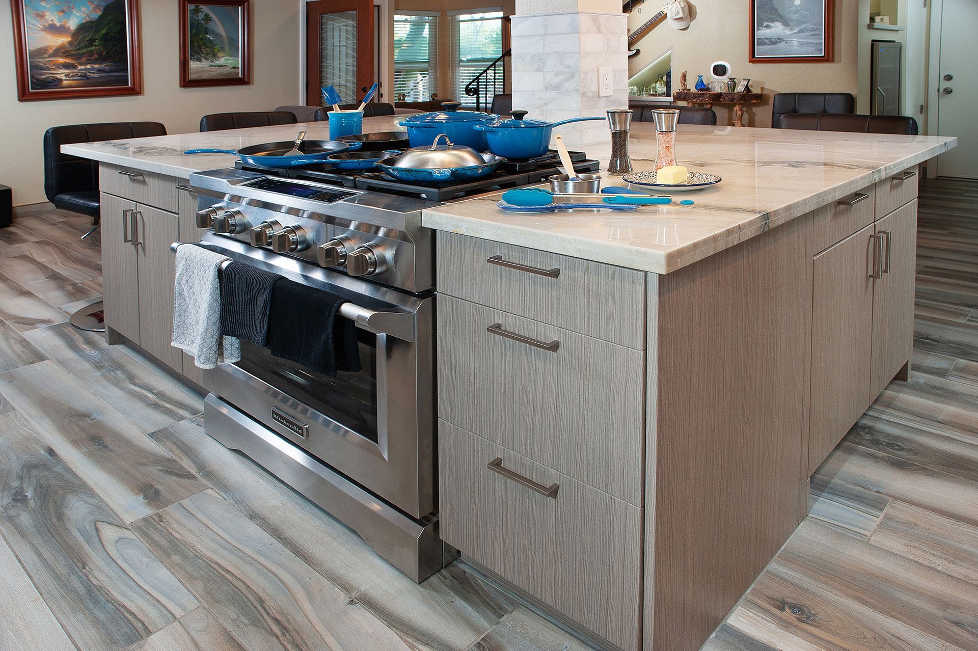 Large kitchen island with a stainless steel stove, light-colored cabinetry, and light wood-look flooring.
