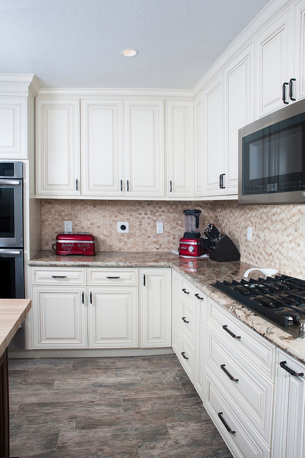 White kitchen with granite counters, red appliances, and a built-in microwave.