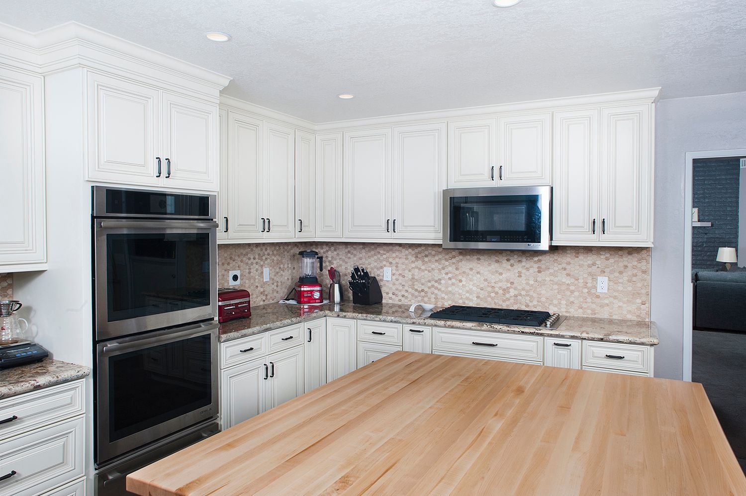 White kitchen with wooden island, cabinets, and stainless steel appliances.