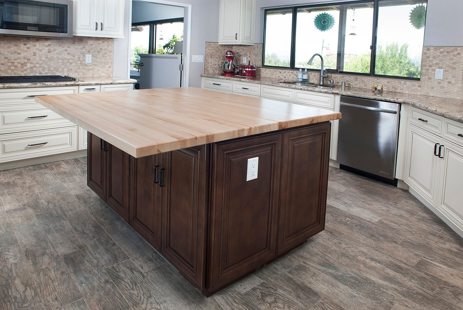 Kitchen with dark brown island, light wood countertop, and white cabinets.