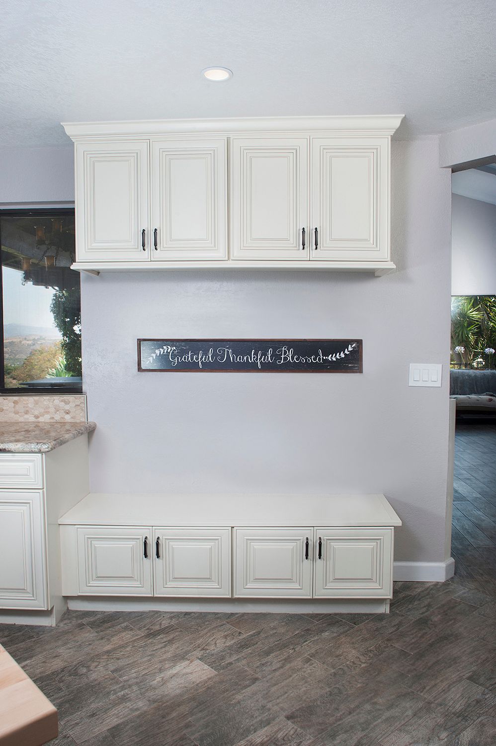White cabinets with bench seating beneath, on gray wall with a sign.