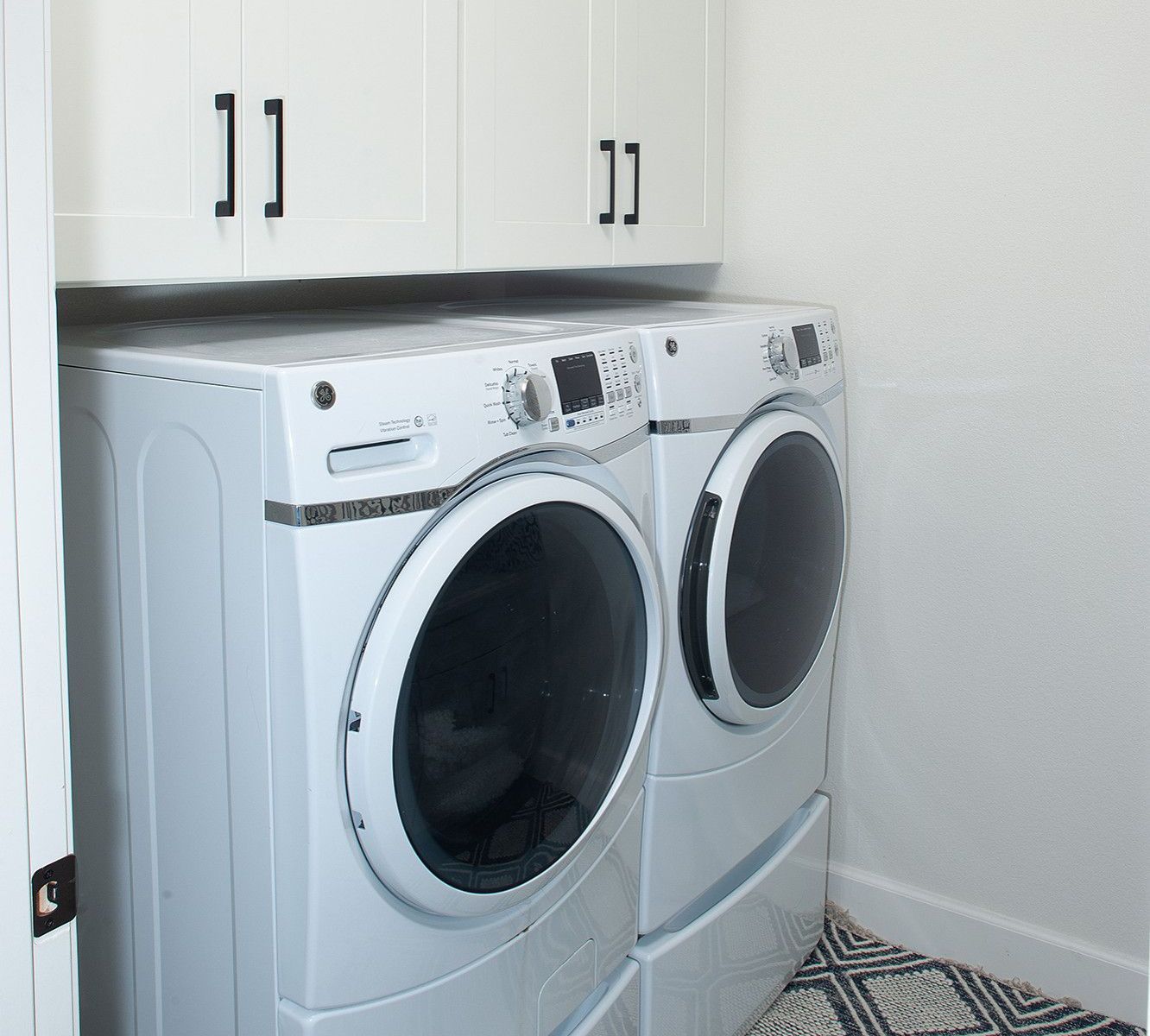 A laundry room with two white washers and dryers.