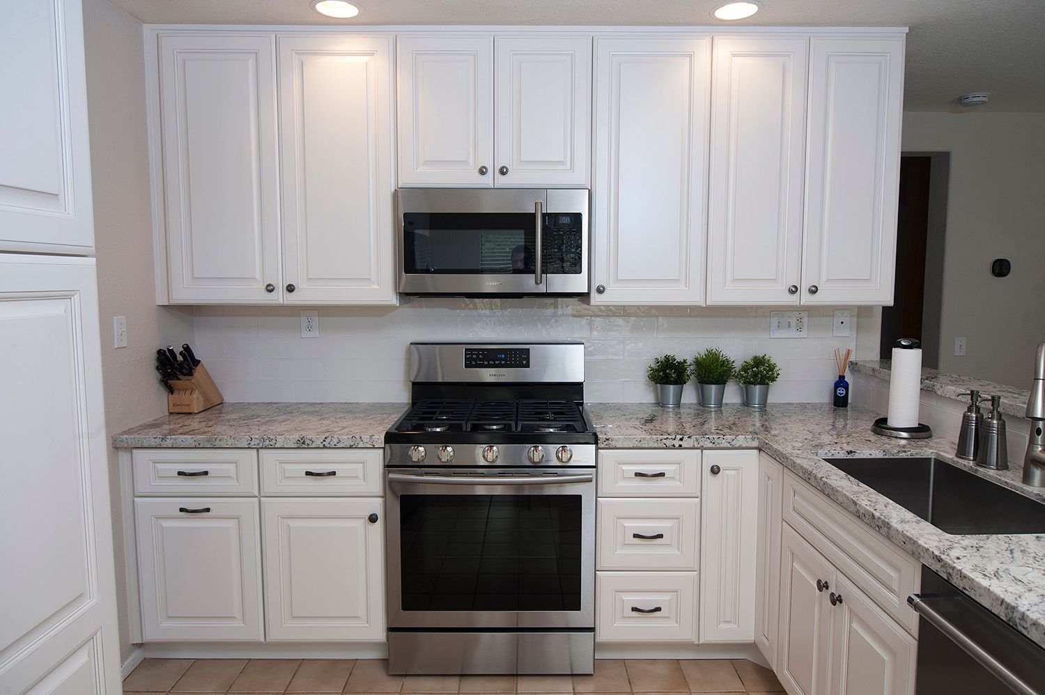 White kitchen cabinets with stainless steel appliances and granite countertops.