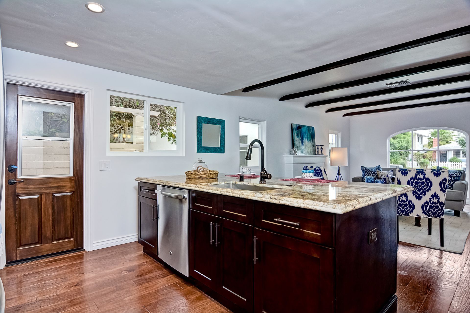 Kitchen with dark cabinets, granite countertop, stainless steel appliances, and open to a dining area.