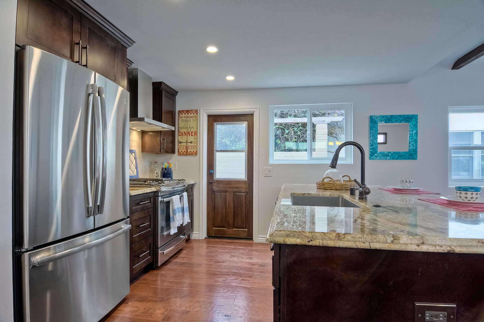 Modern kitchen with stainless steel appliances, brown cabinets, granite countertop, and copper-colored floor.