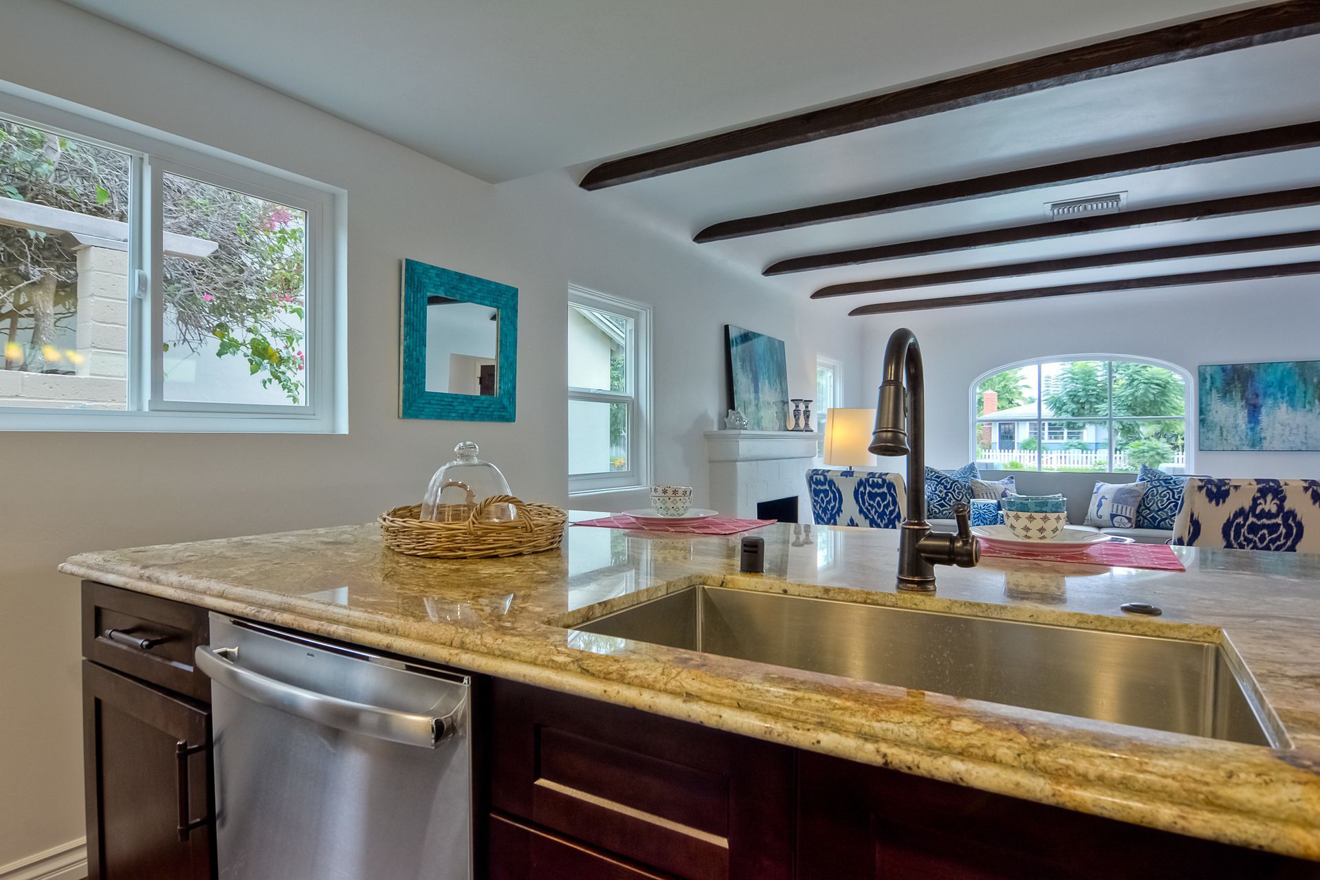 Kitchen with granite countertop, stainless steel sink, and dark wood cabinets. View to living area.