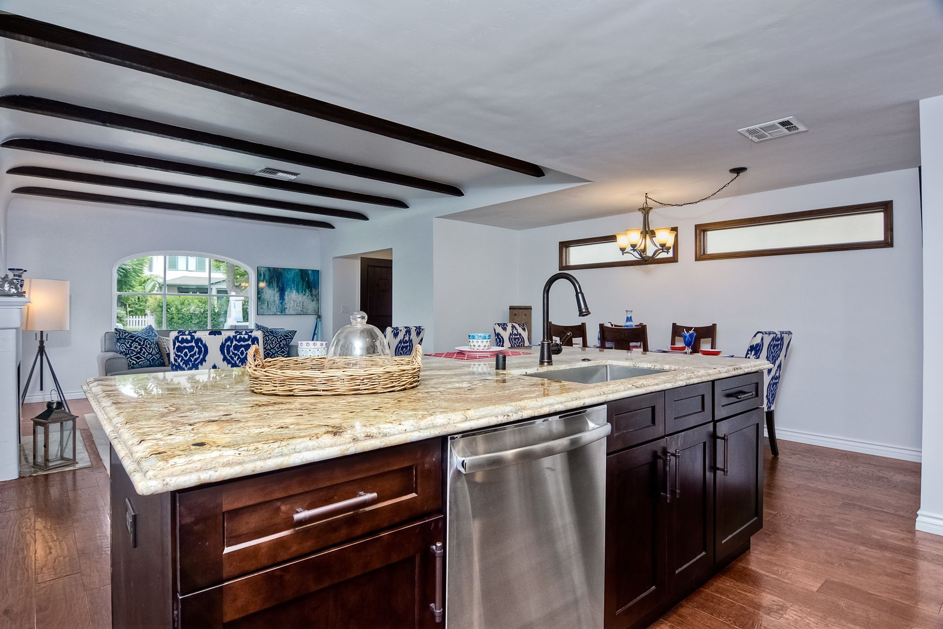 Kitchen island with granite countertop, dark cabinets, and stainless steel appliances; open to living and dining areas.