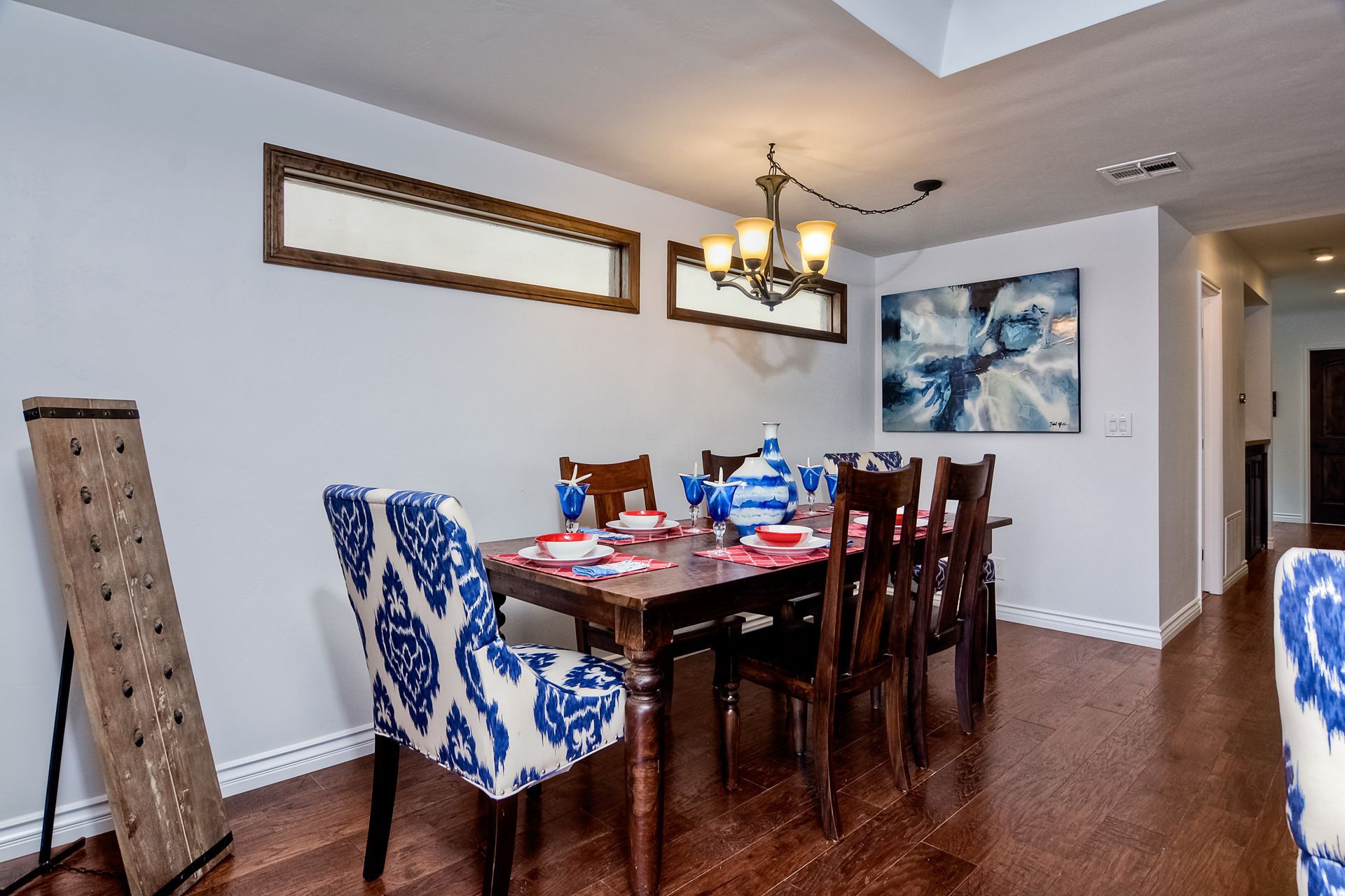 Dining room with a wooden table, blue patterned chairs, and a chandelier.