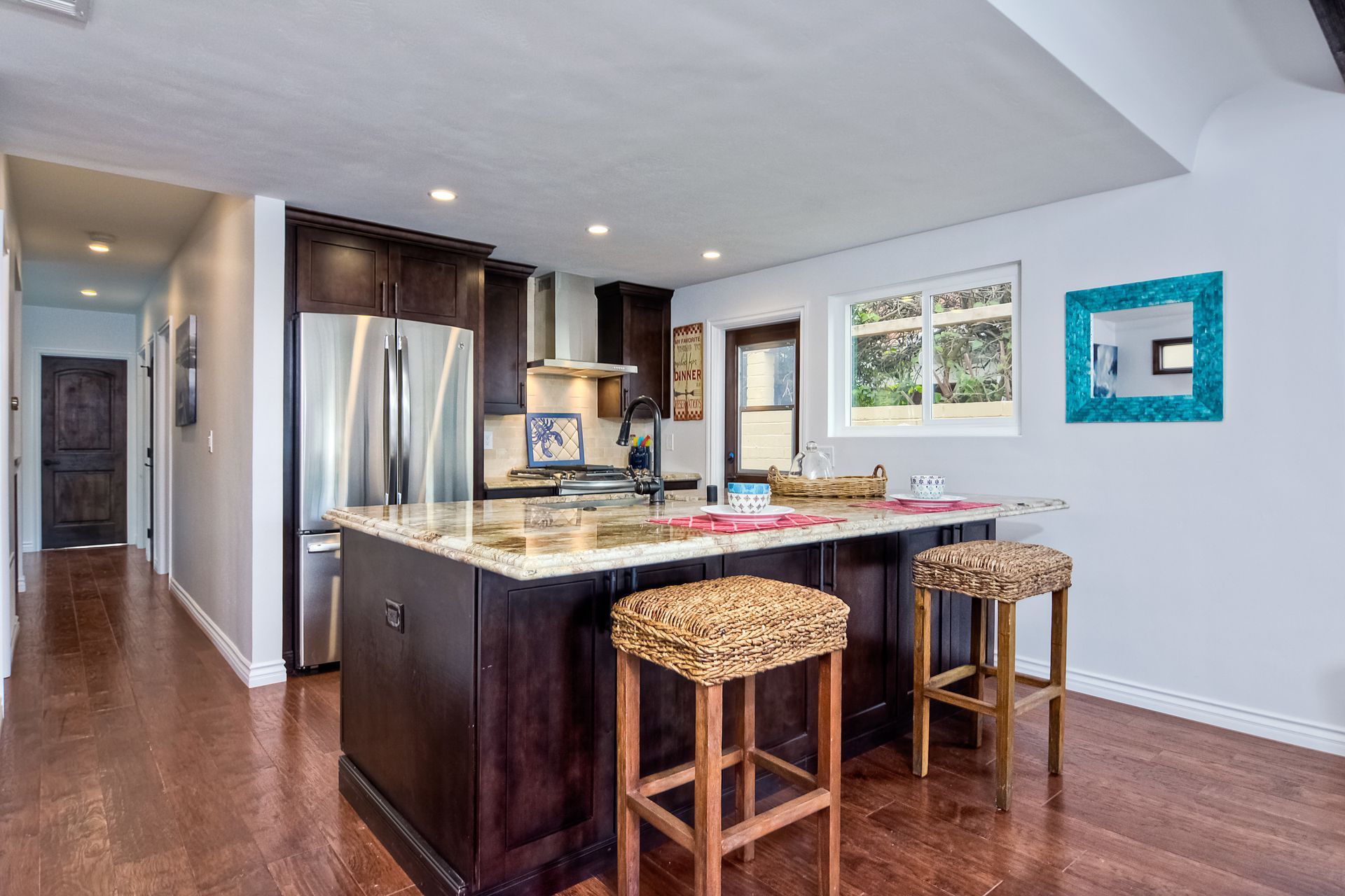 Kitchen with island, dark cabinets, stainless steel appliances, and two leopard-print stools.
