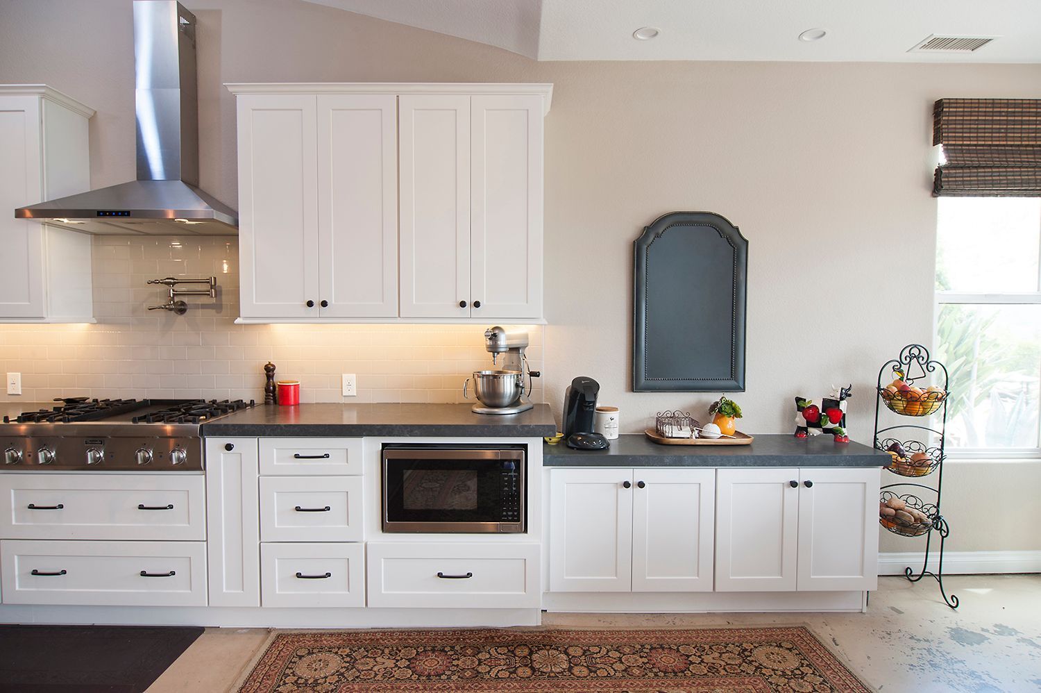 White kitchen cabinets with stainless steel appliances and decor against a light wall.