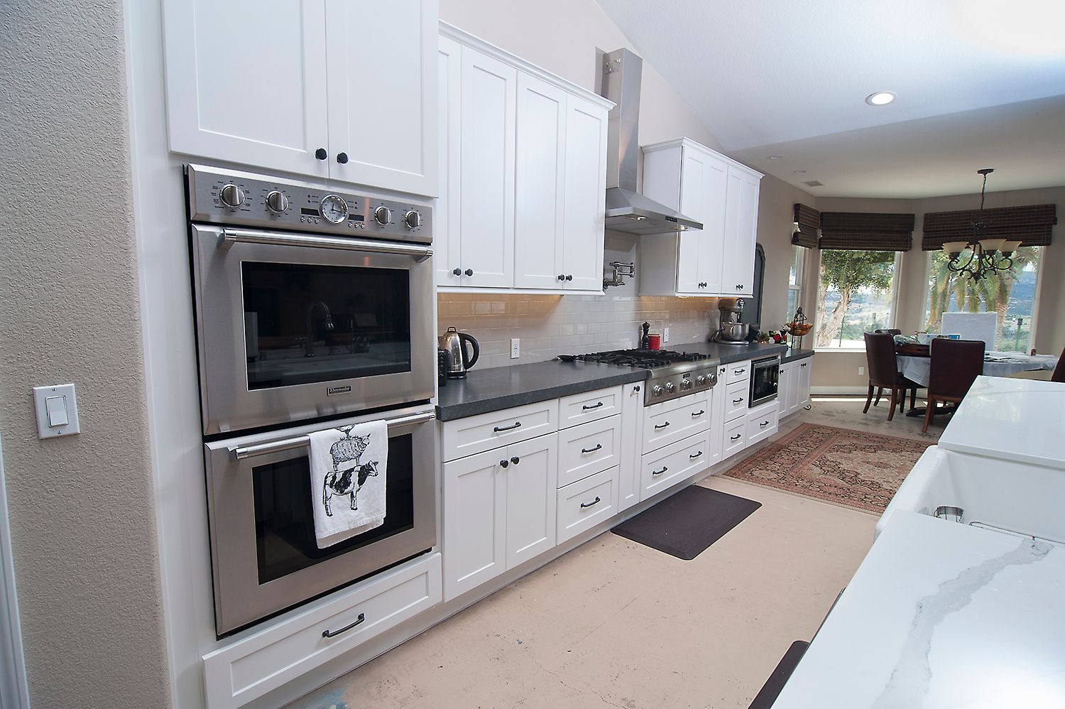 White kitchen with stainless steel appliances and dark countertops.