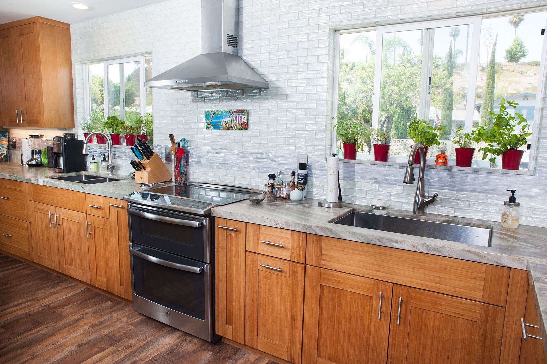 Kitchen with wooden cabinets, stainless steel appliances, and a brick-like backsplash. Windows with plants.