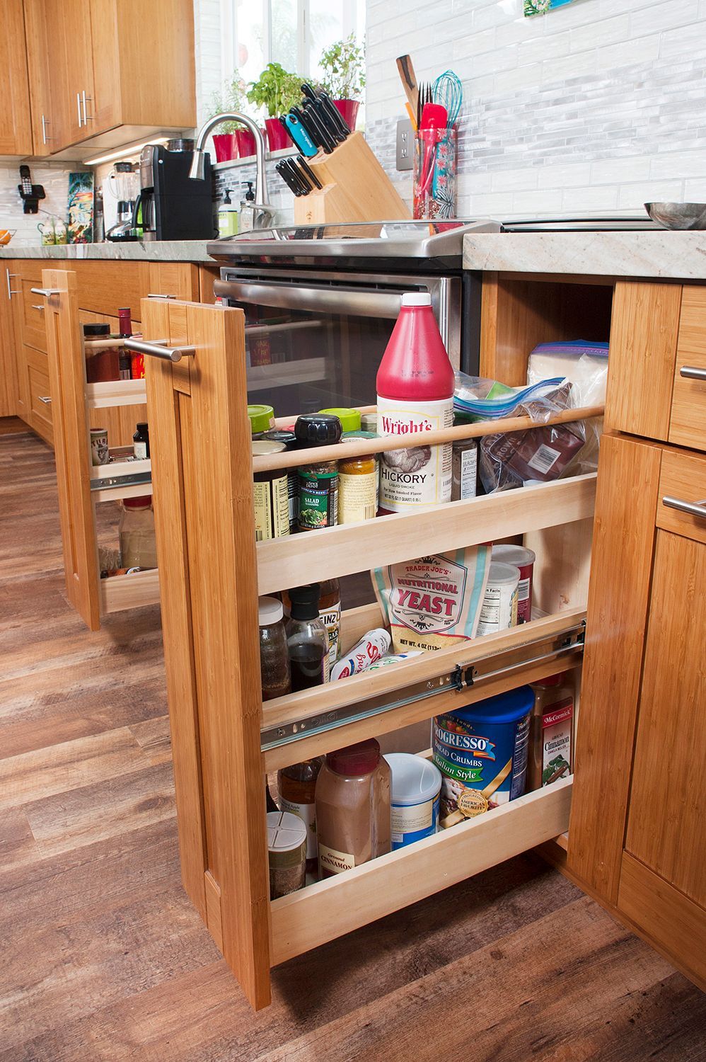 Pull-out kitchen cabinet with spice and food storage; wooden construction, light brown, near stove.