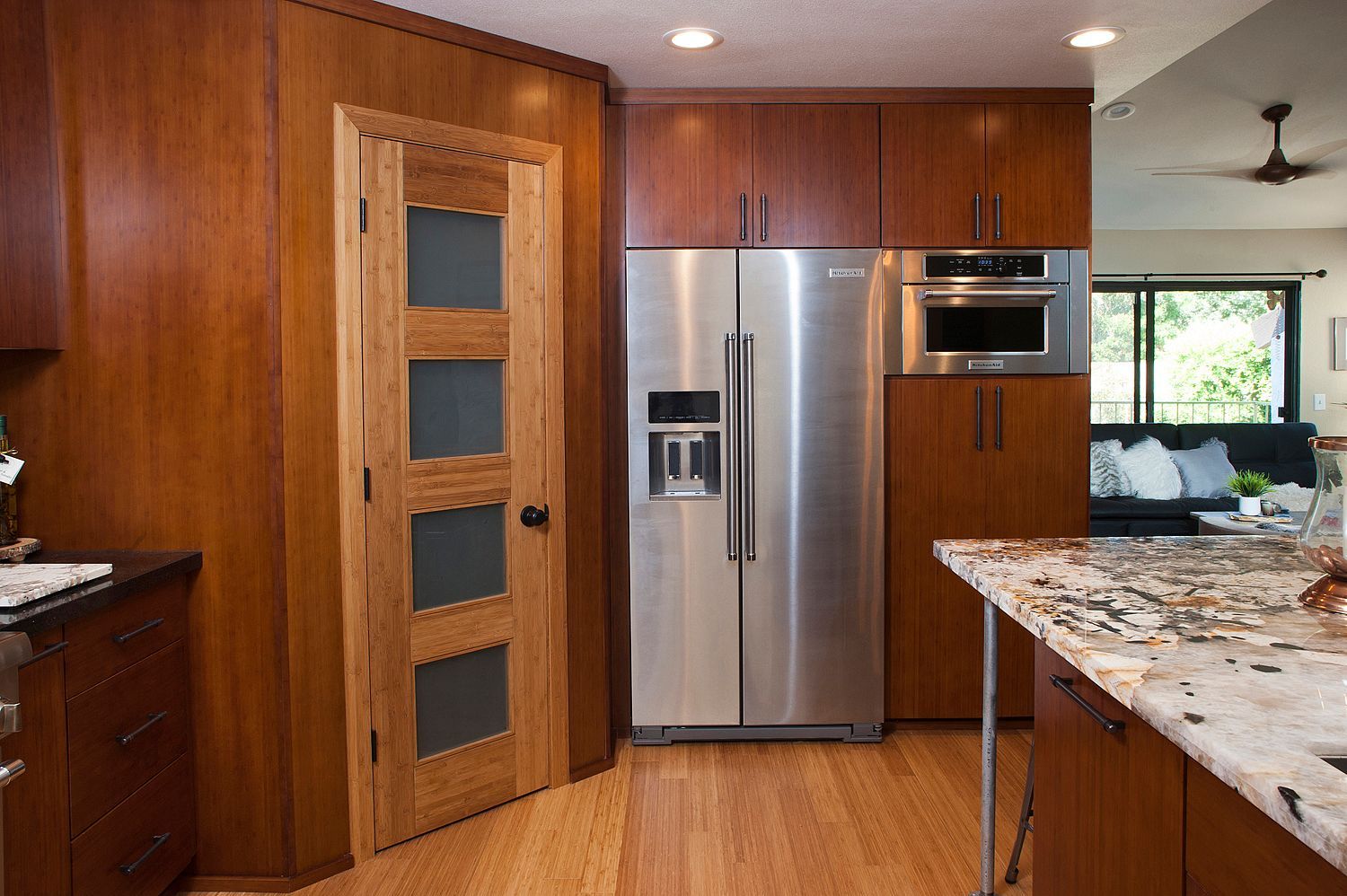 Kitchen with stainless steel refrigerator, built-in microwave, wooden cabinets and a light wood door.