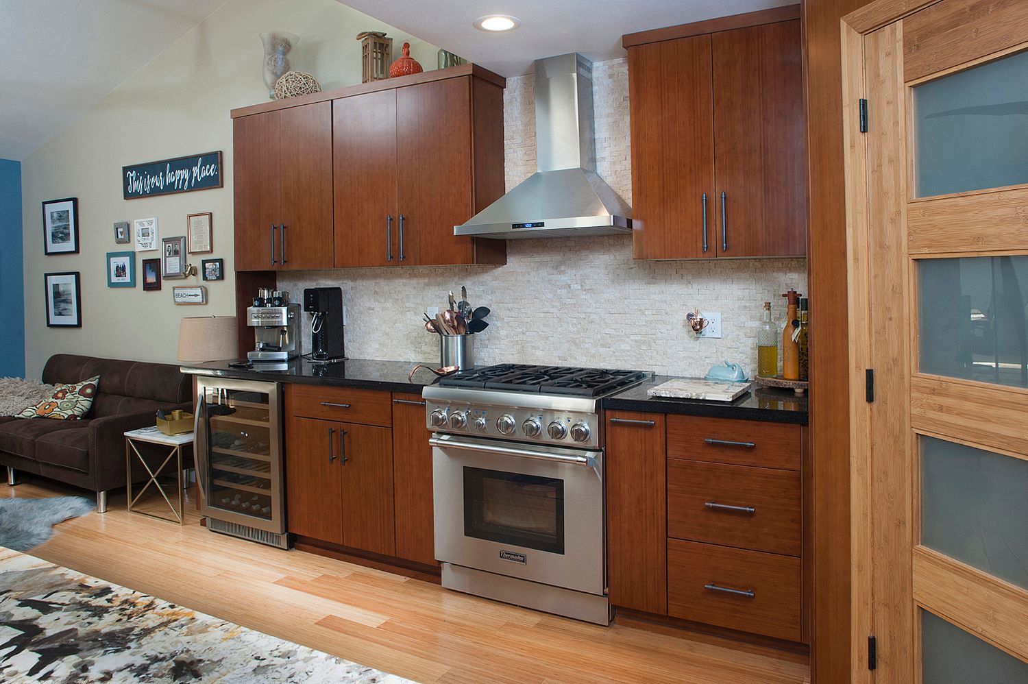 Kitchen with stainless steel appliances, brown cabinets, black countertops, and a wooden door.