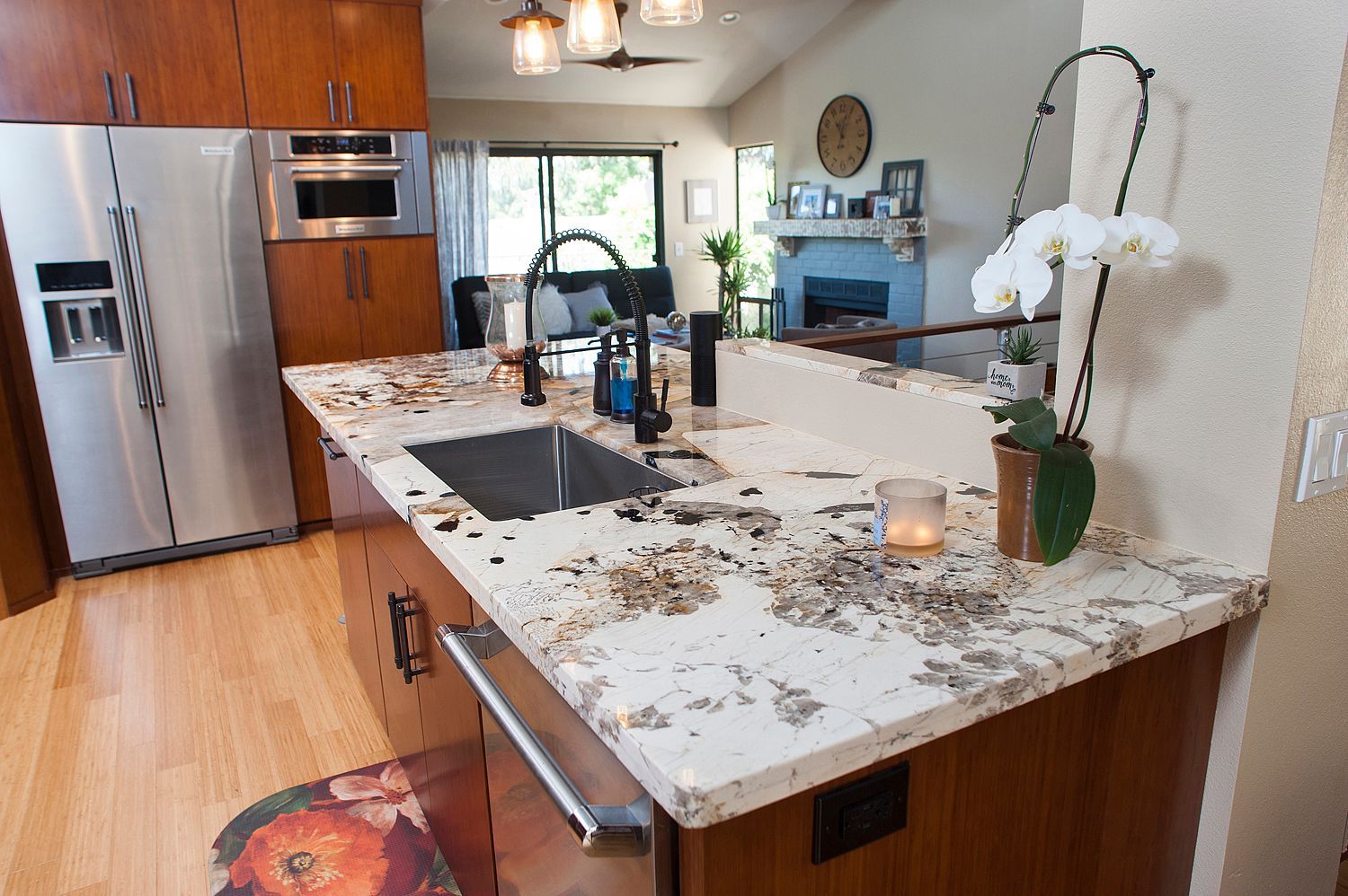 Kitchen with granite countertop, sink, stainless steel refrigerator, and an orchid.