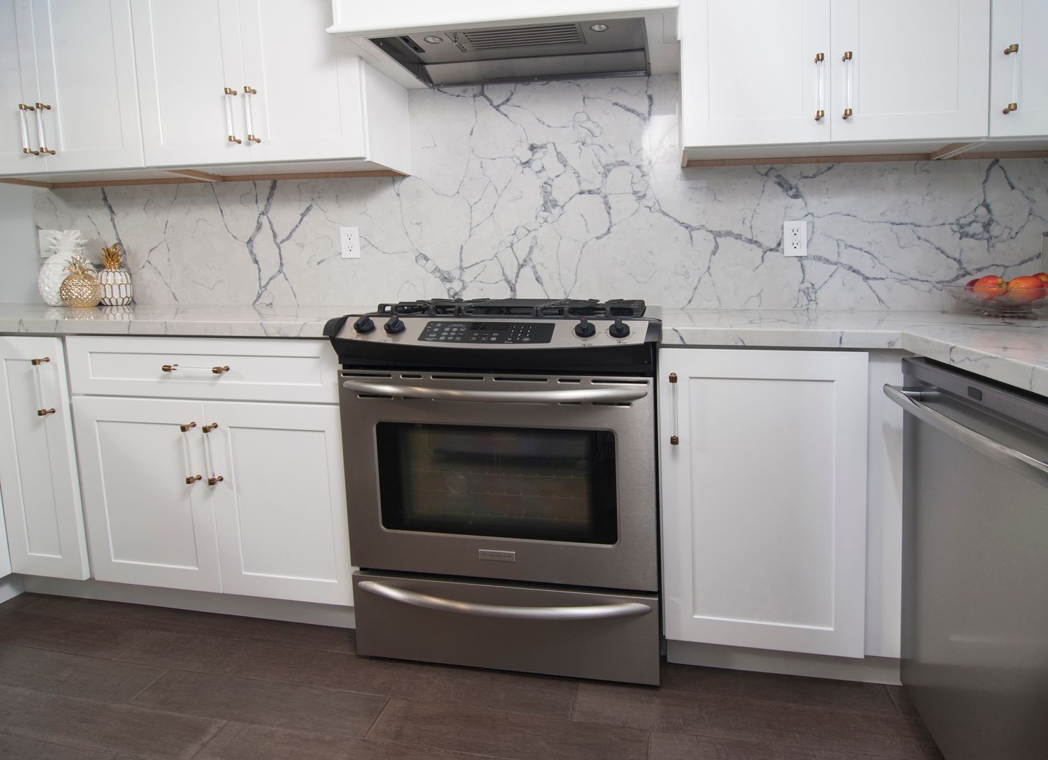Stainless steel oven in white kitchen with marble backsplash and cabinets.