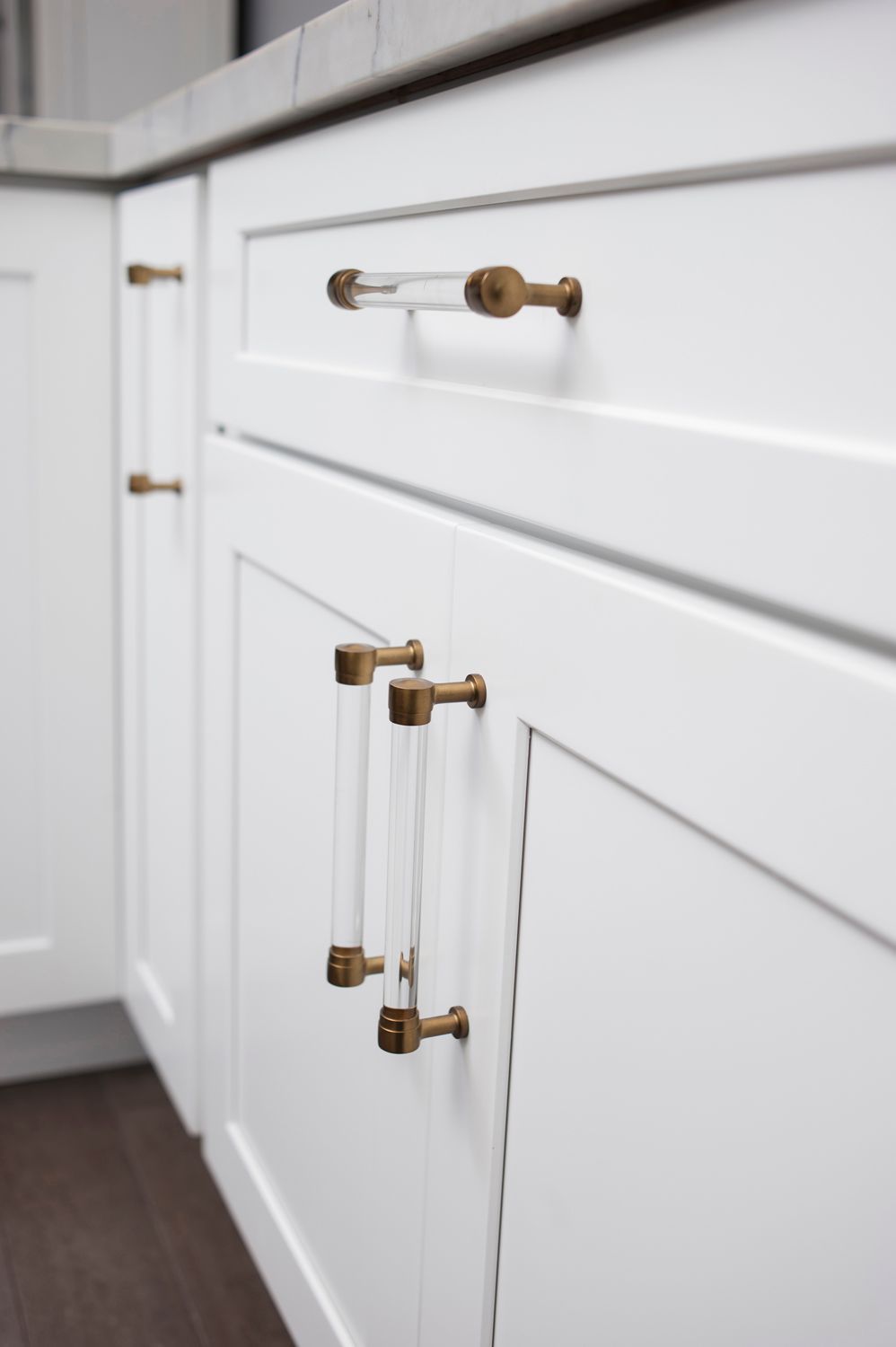 White kitchen cabinets with clear and gold hardware.