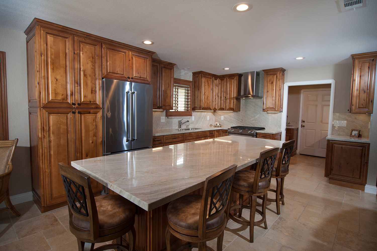 Kitchen with wood cabinets, stainless steel appliances, large island with seating, and tile flooring.