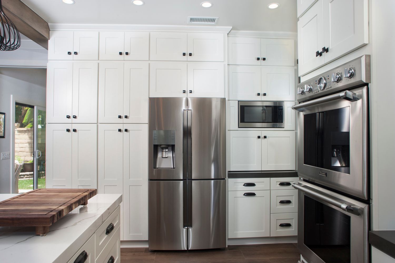 White kitchen with stainless steel appliances and cabinets; a refrigerator, microwave, and oven are visible.