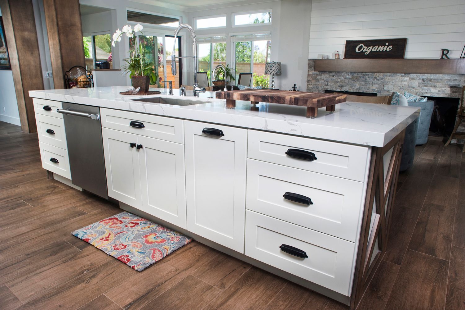 White kitchen island with integrated appliances and wooden accents.