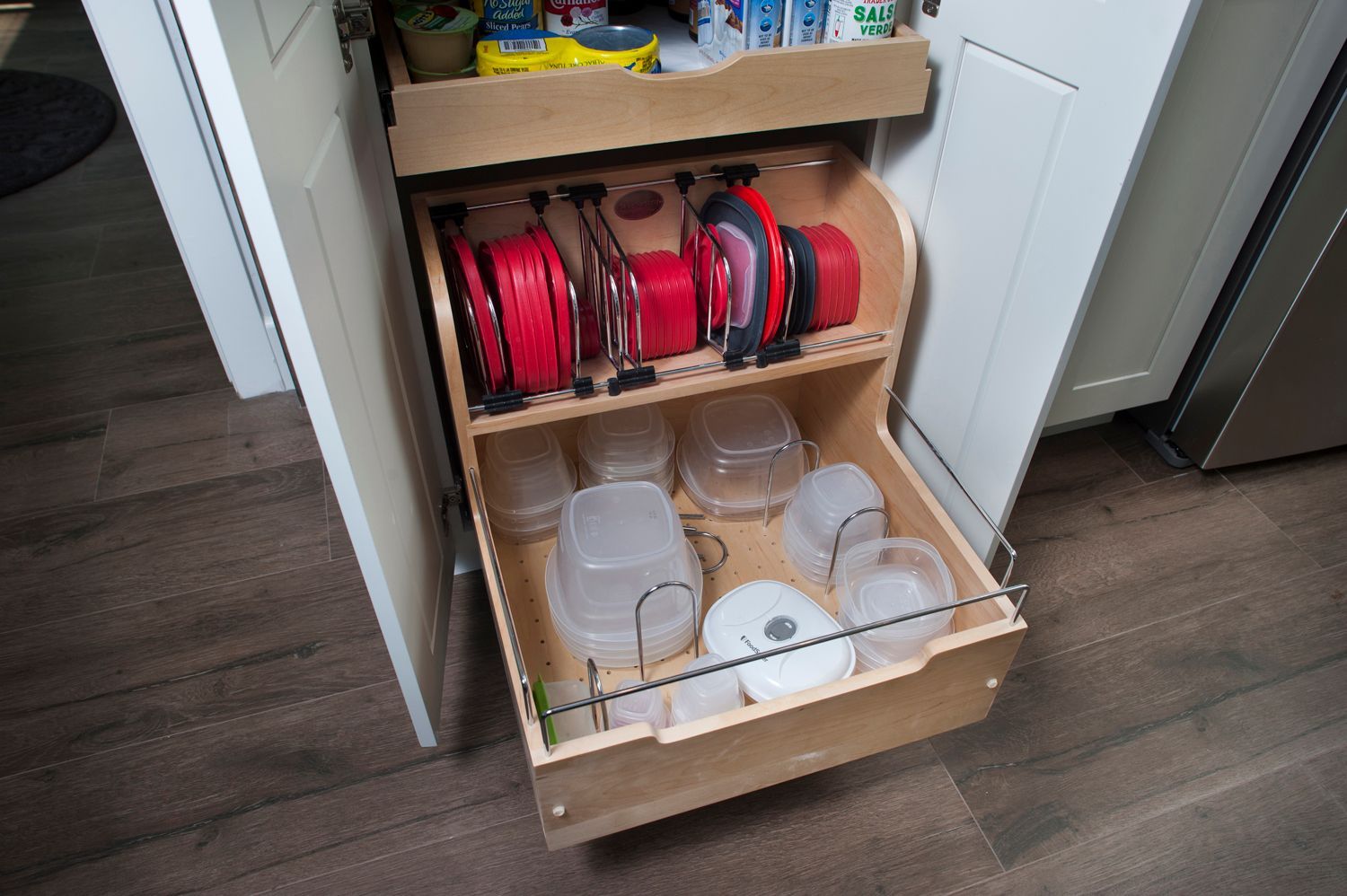 Pull-out kitchen cabinet organizer with food storage containers and lids neatly arranged inside.