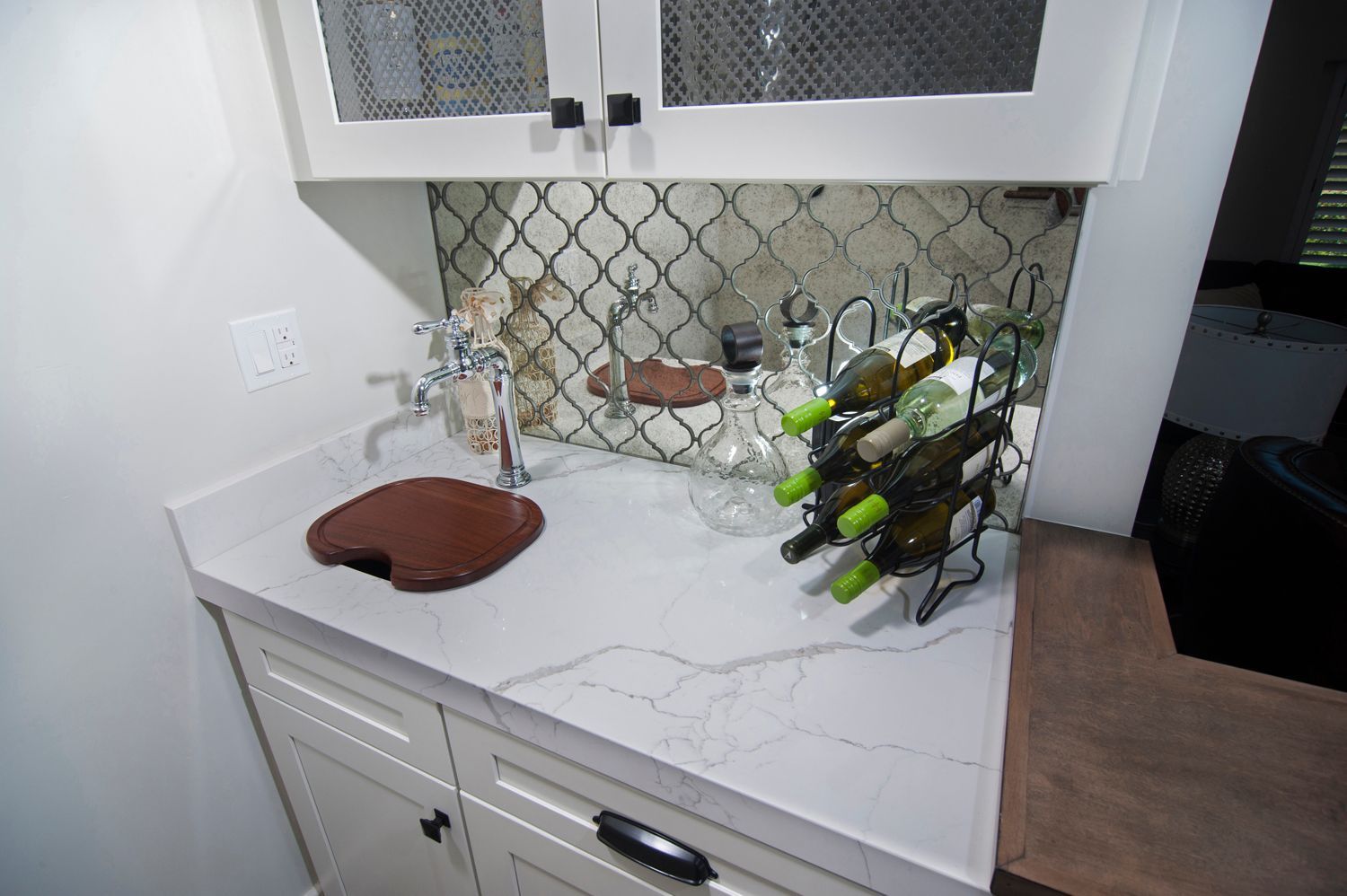 Small white bar area with wine rack, faucet, and decorative backsplash under cabinets.