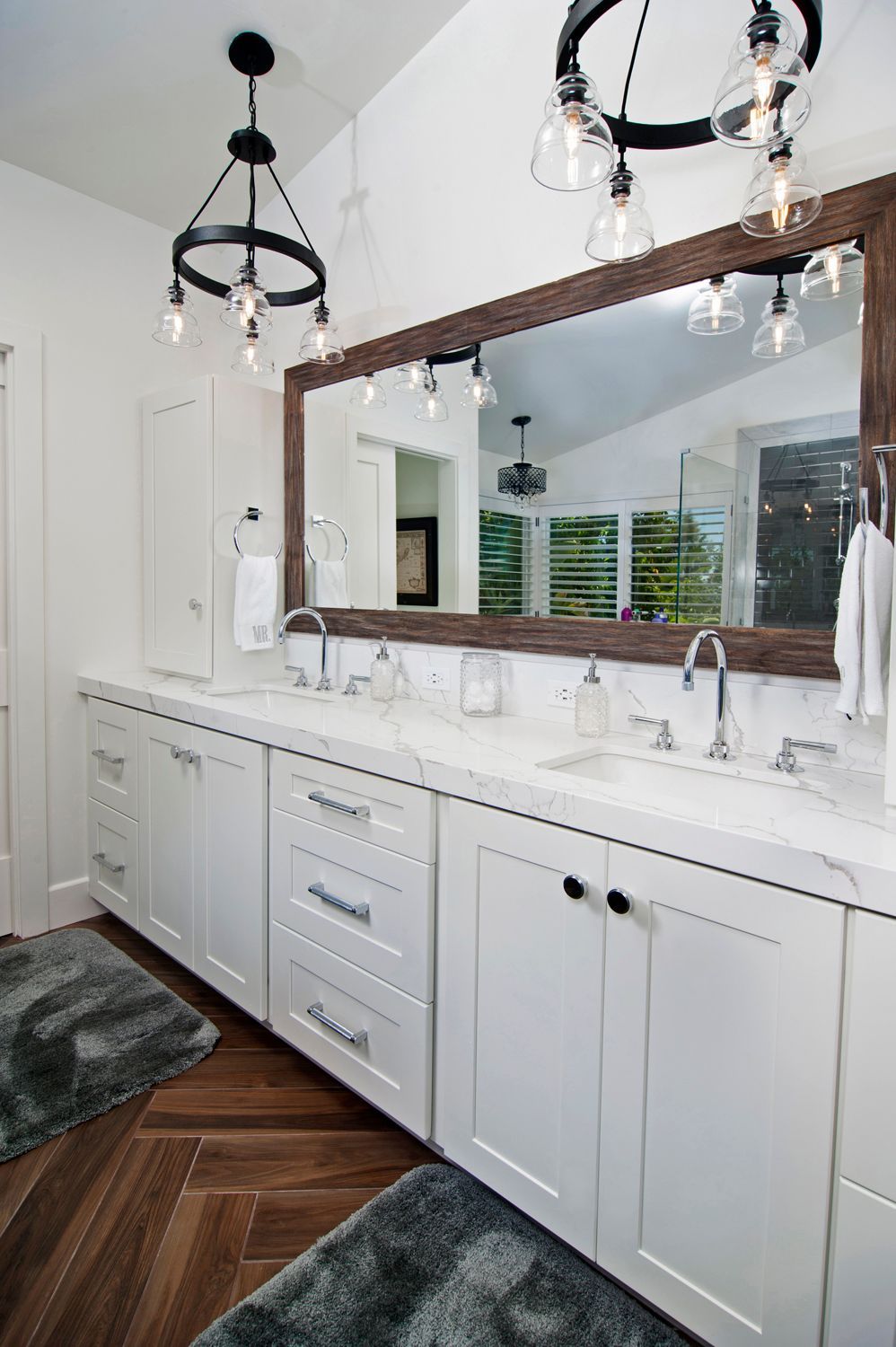 Bathroom with white cabinets, marble counter, large mirror, and two black light fixtures.